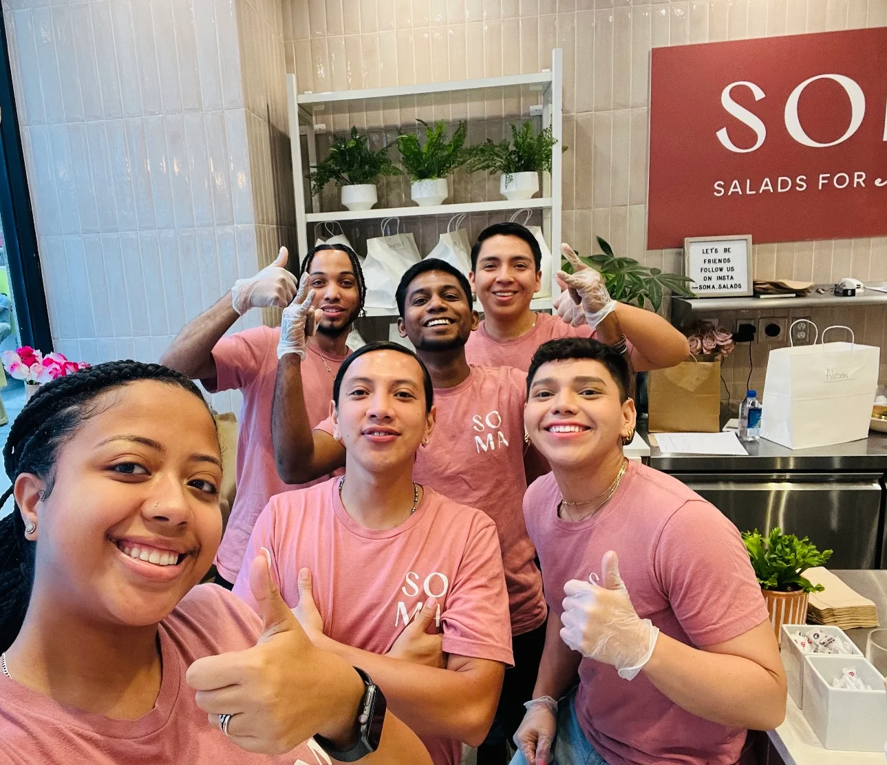 Cheerful staff at a salad restaurant posing for a group photo