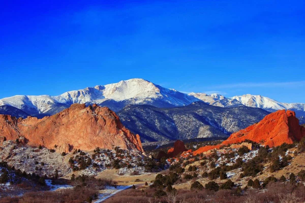 Scenic view of snow-capped mountains and red rock formations under a clear blue sky