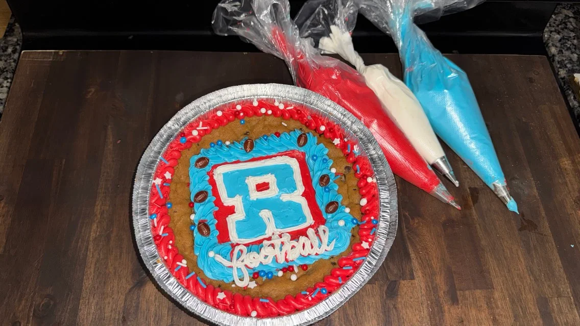 Decorative football-themed cookie cake with colorful icing and toppings