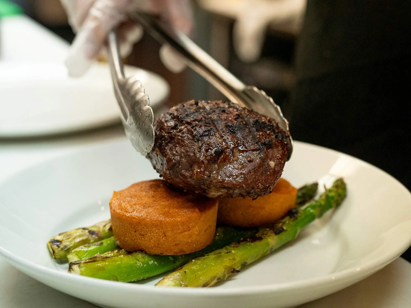 A beautifully plated steak dish with garnishes on a wooden table.
