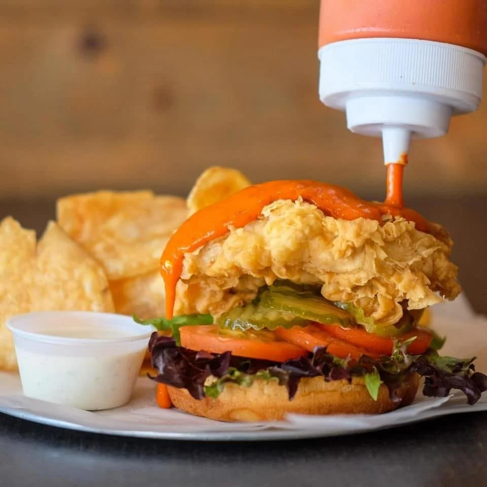 Crispy fried chicken sandwich with spicy sauce and potato chips