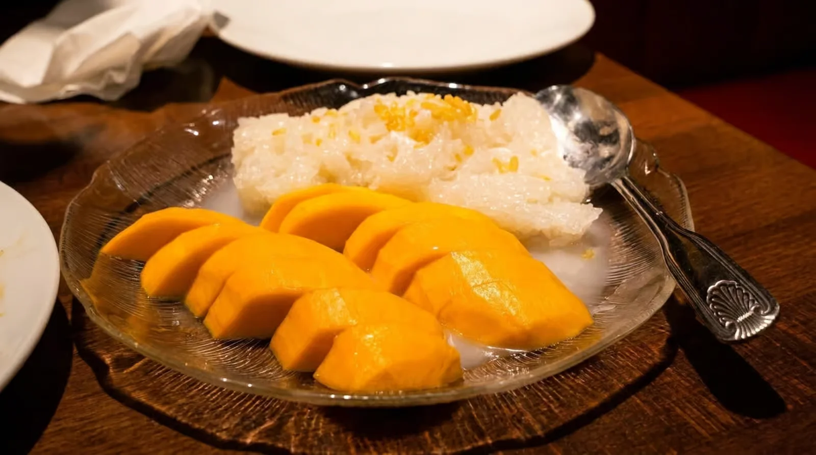 Thai mango sticky rice dessert served on a glass plate