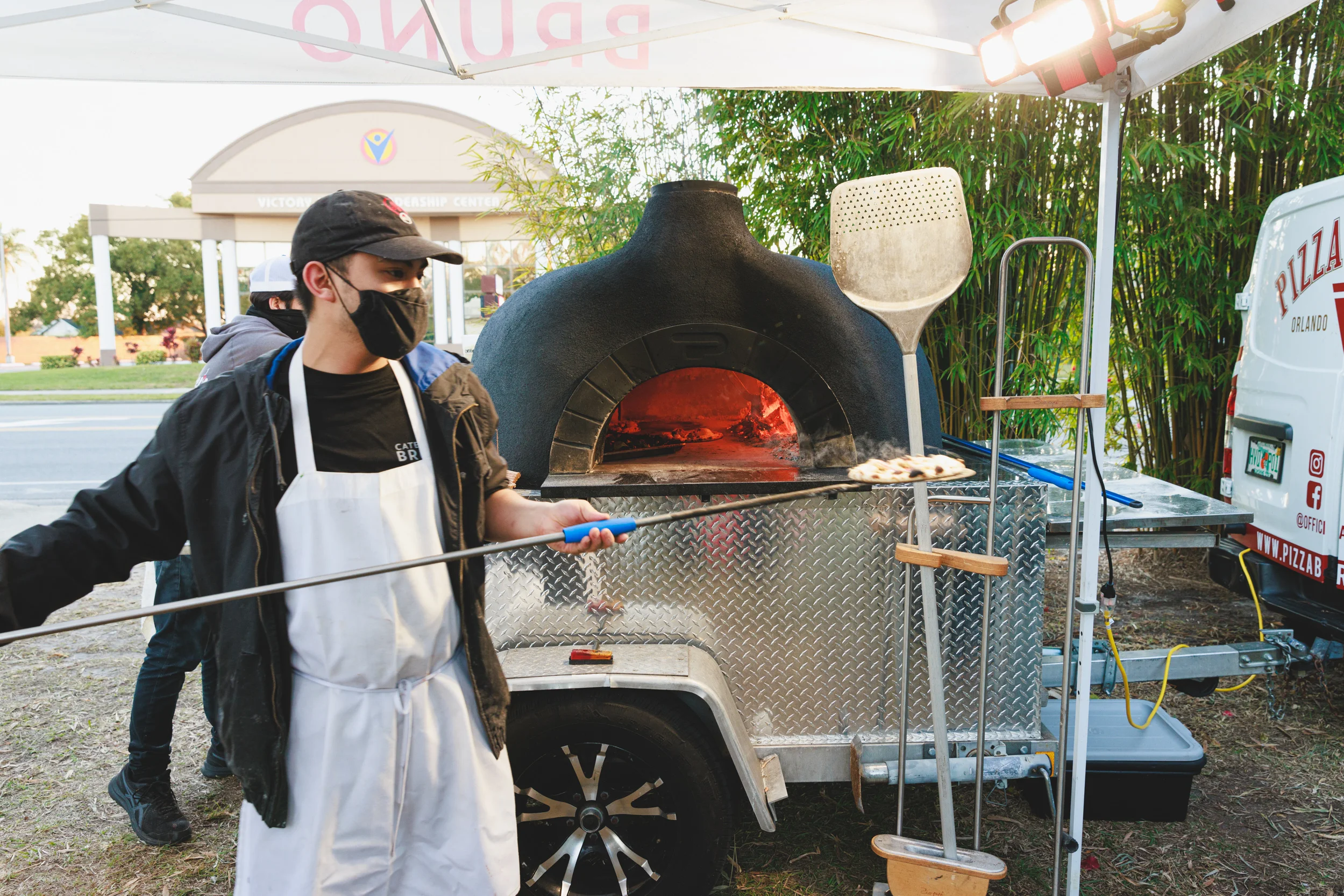 Chef preparing Margherita pizza in a wood-fired oven