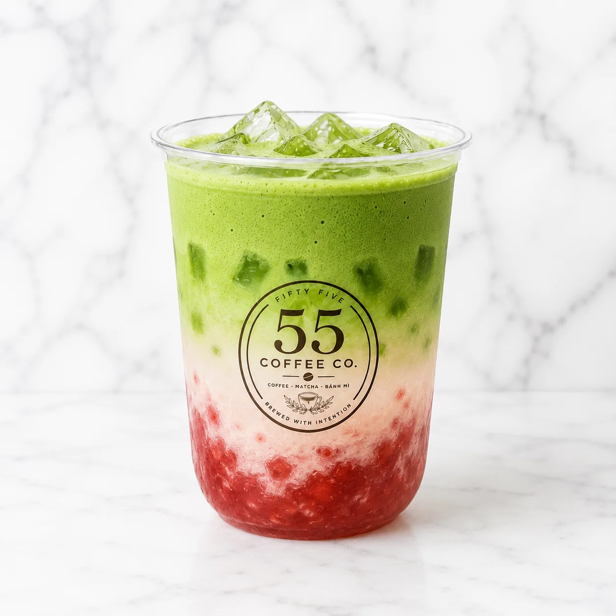 Layered matcha and strawberry drink in a clear cup