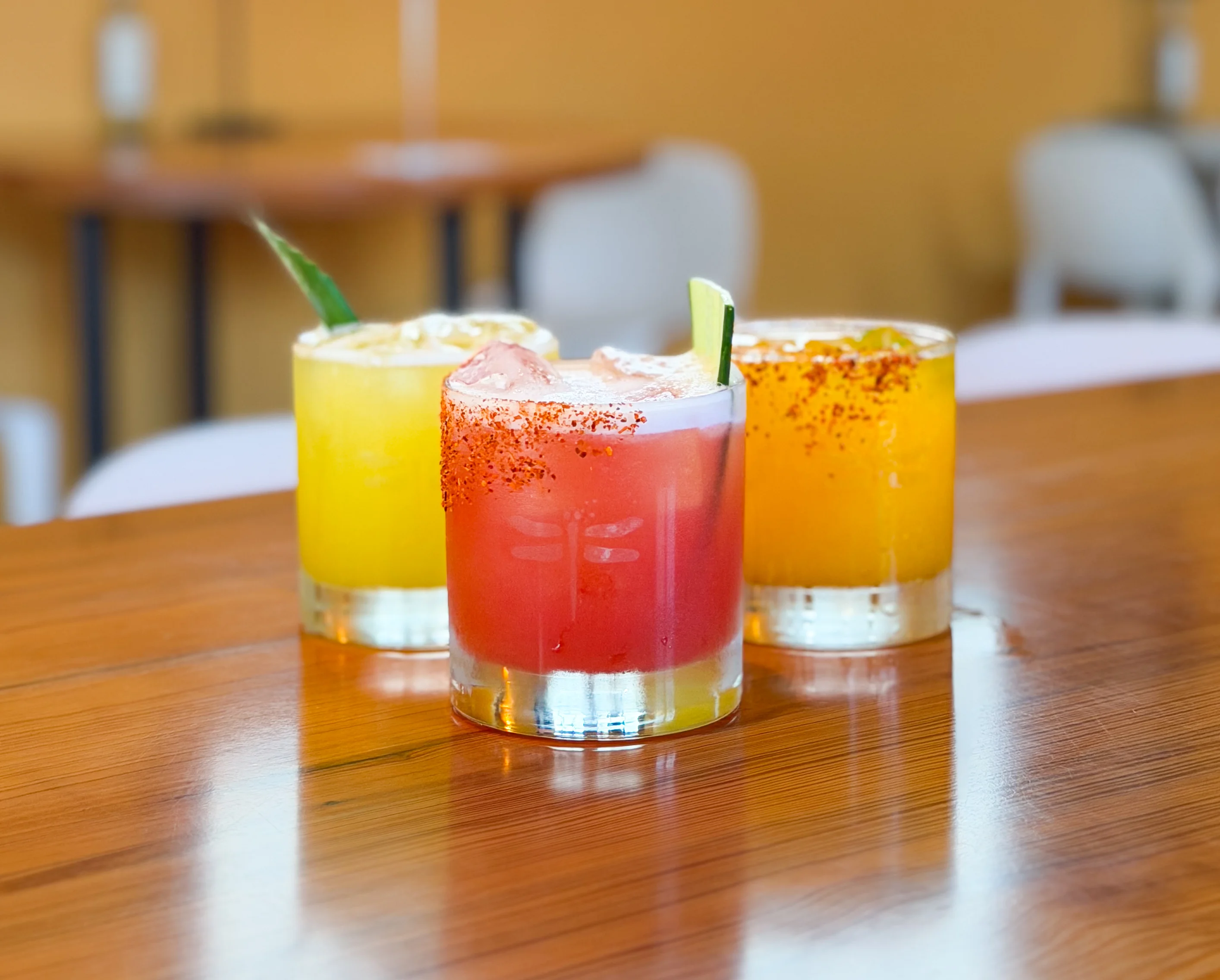 Colorful cocktails on a wooden table in a vibrant restaurant setting