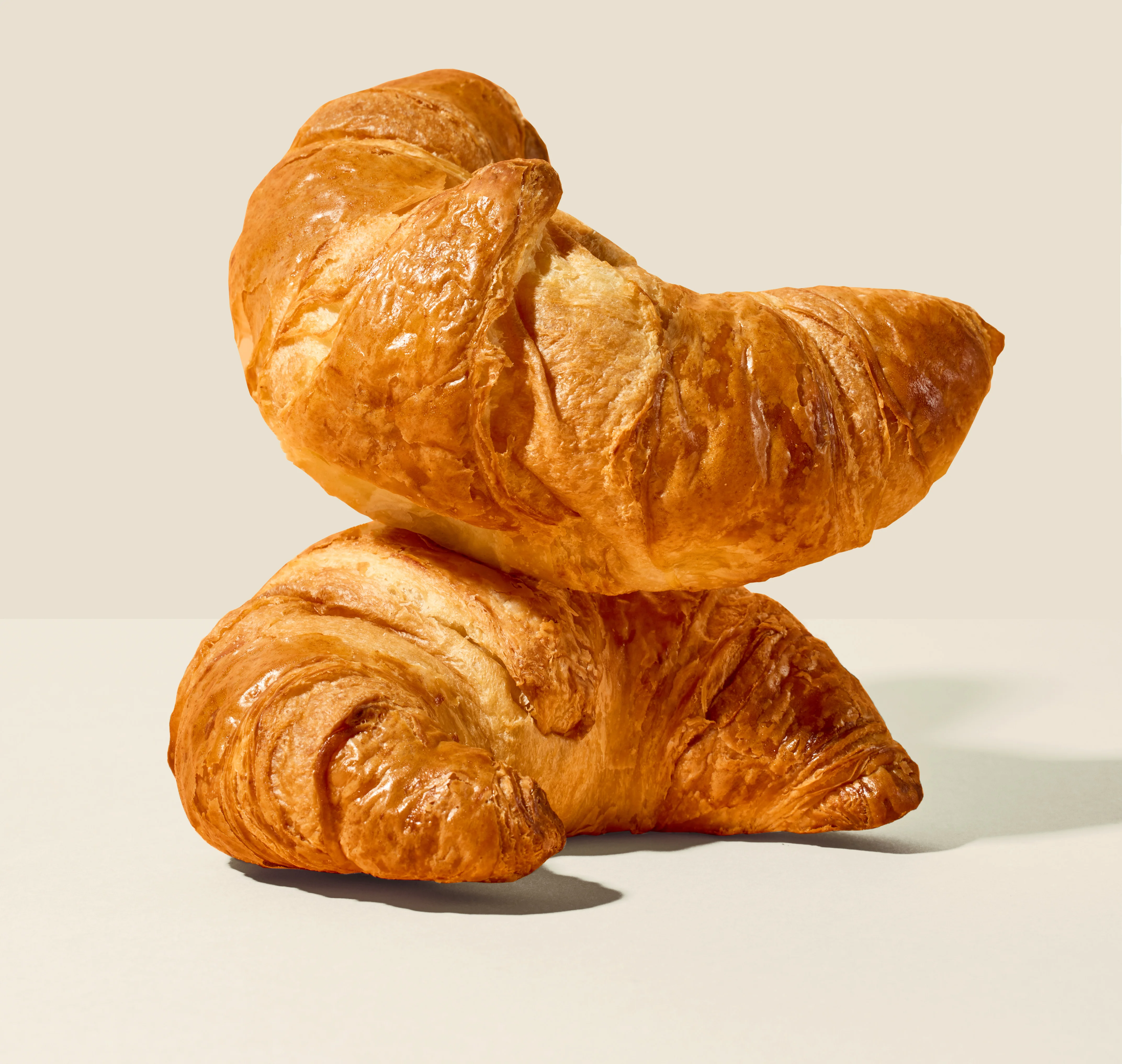 Freshly baked French croissants stacked on a neutral background