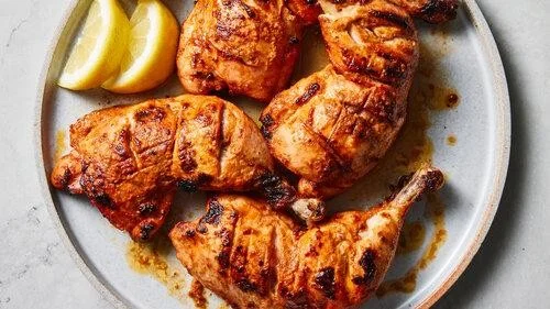 Grilled Mediterranean chicken with lemon wedges