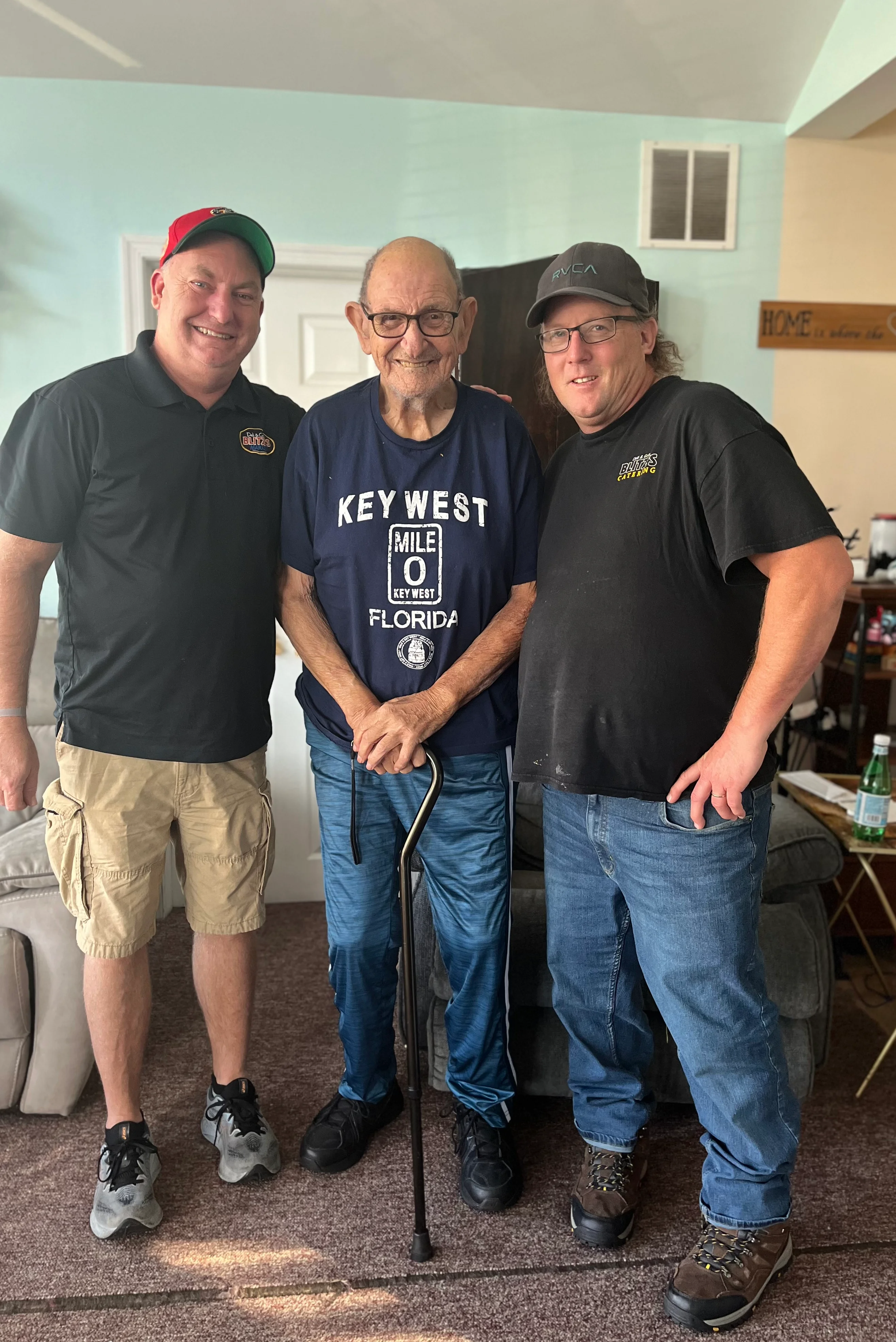 Three men posing together in a cozy living room setting