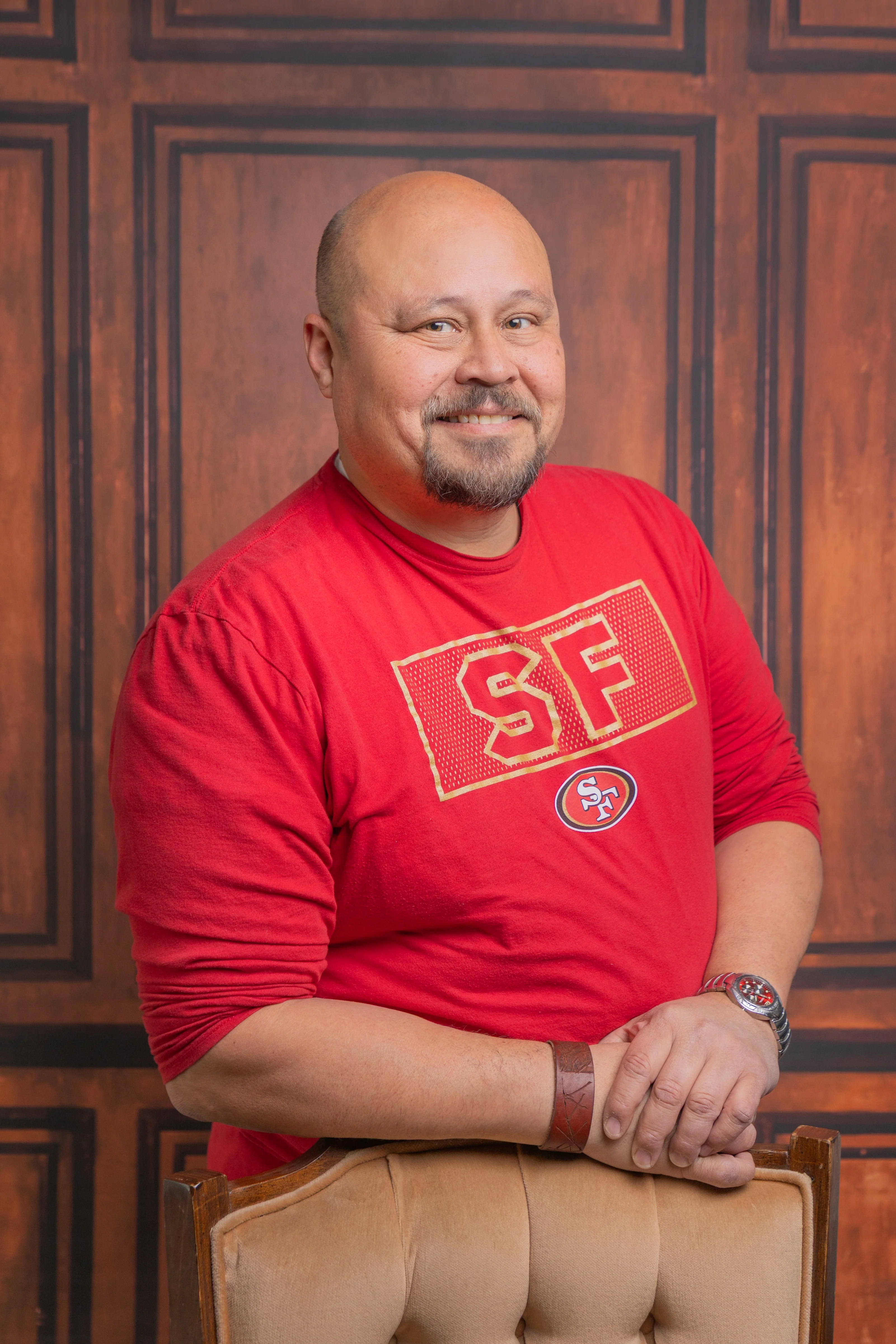 Smiling man in a red SF shirt posing in a cozy restaurant setting