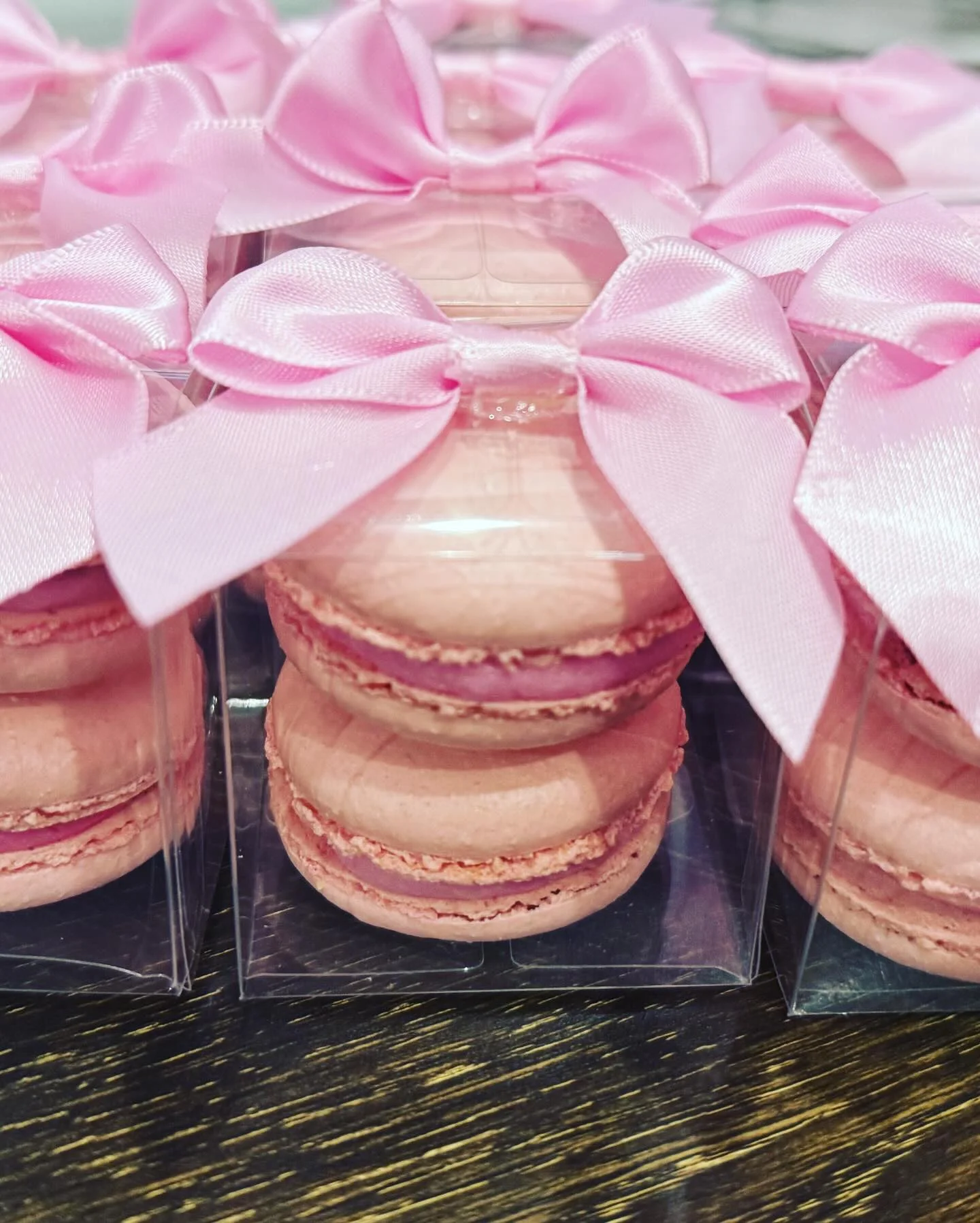 Elegant pink macarons in clear packaging with bows