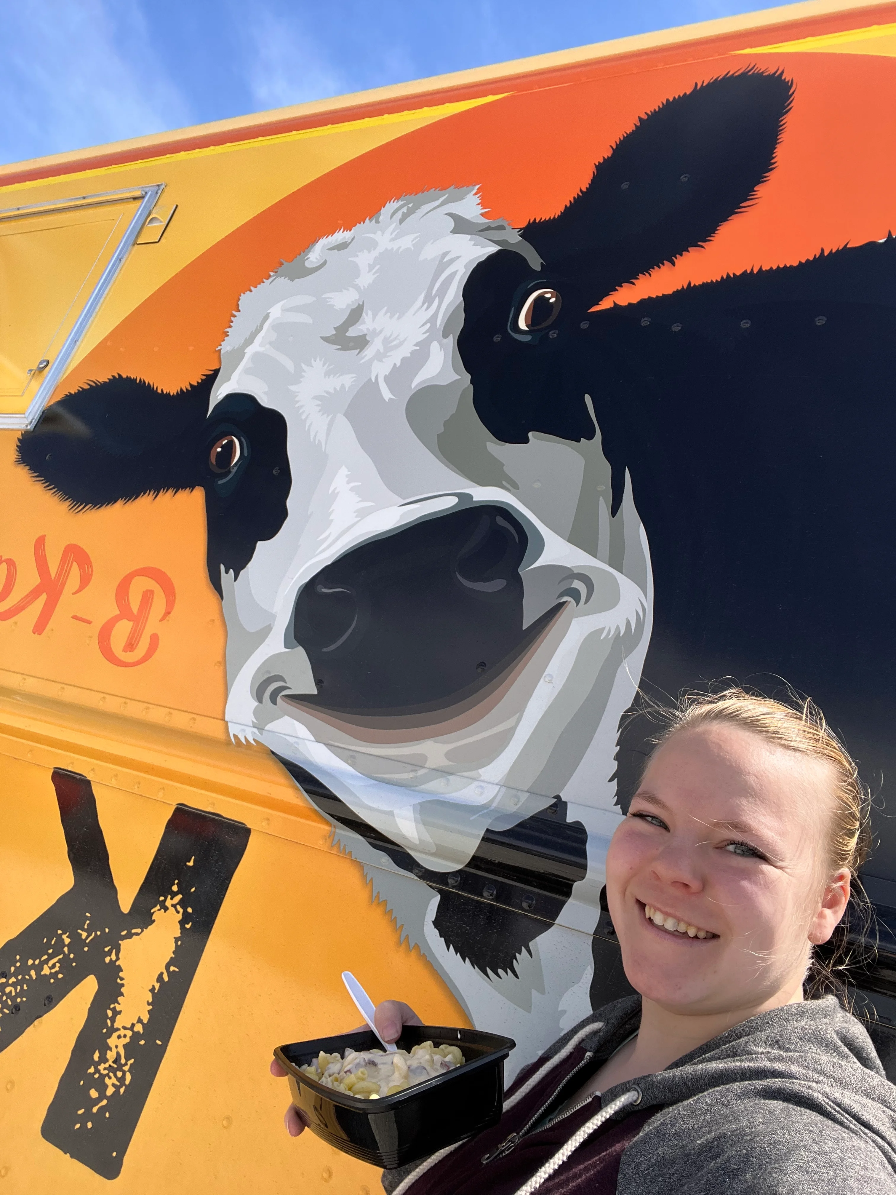 Delicious mac and cheese from a food truck with a cow mural