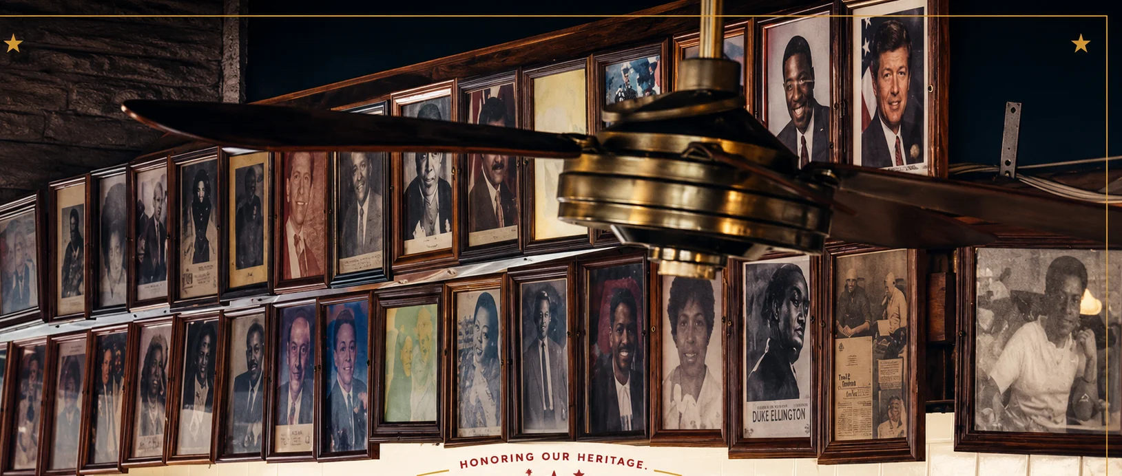 Historic restaurant wall with framed portraits, vintage ceiling fan, and heritage typography