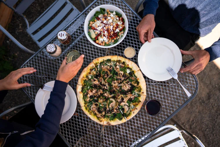 A table with pizza, salad, and drinks, enjoyed outdoors at Frankie's Pizza Mendocino California.