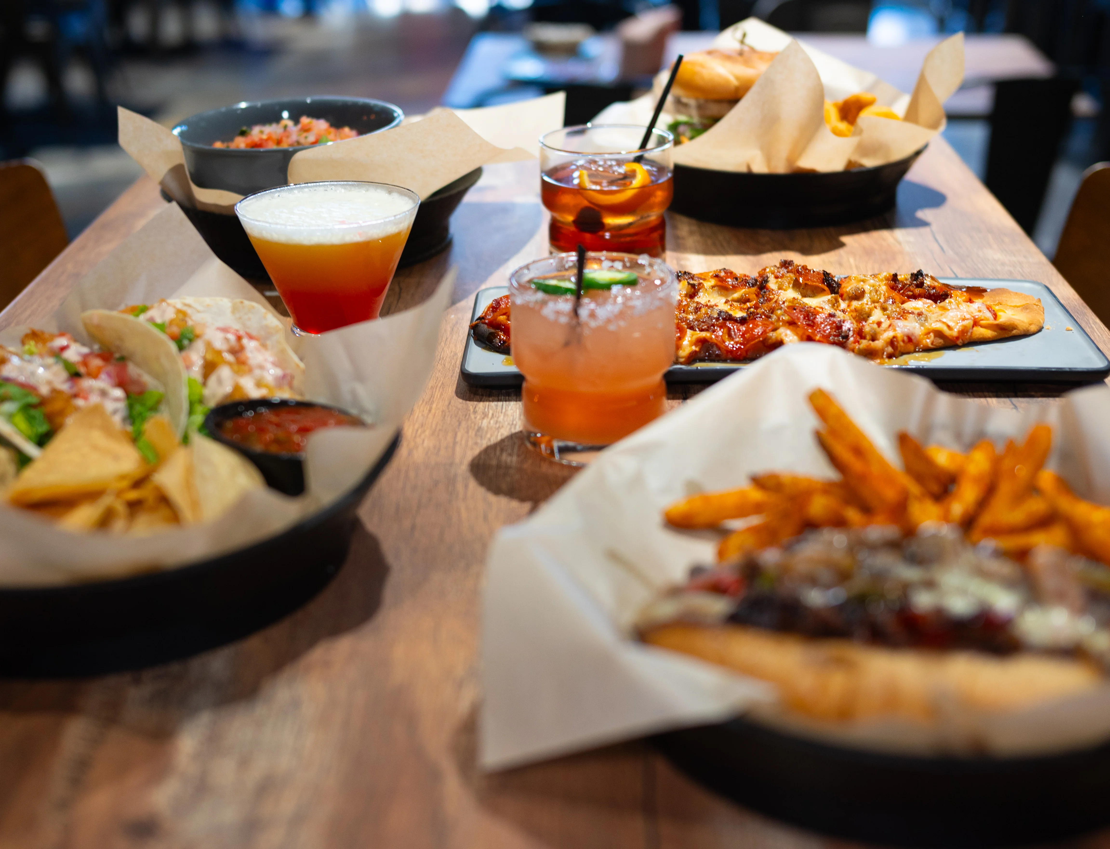 Assorted American comfort food with nachos, pizza, and cocktails