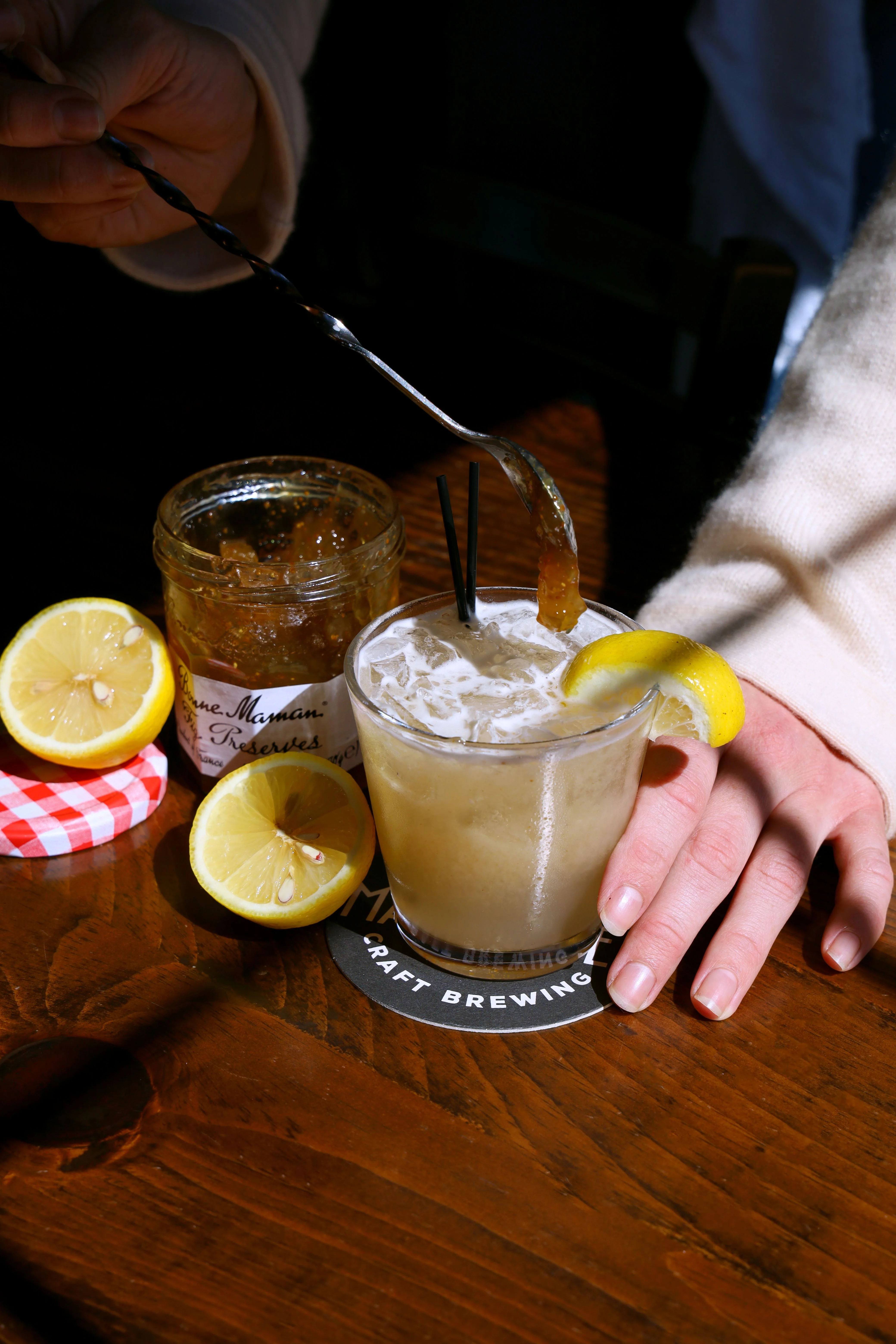 Dark close-up of iced citrus cocktails with lemon garnishes on a wooden bar