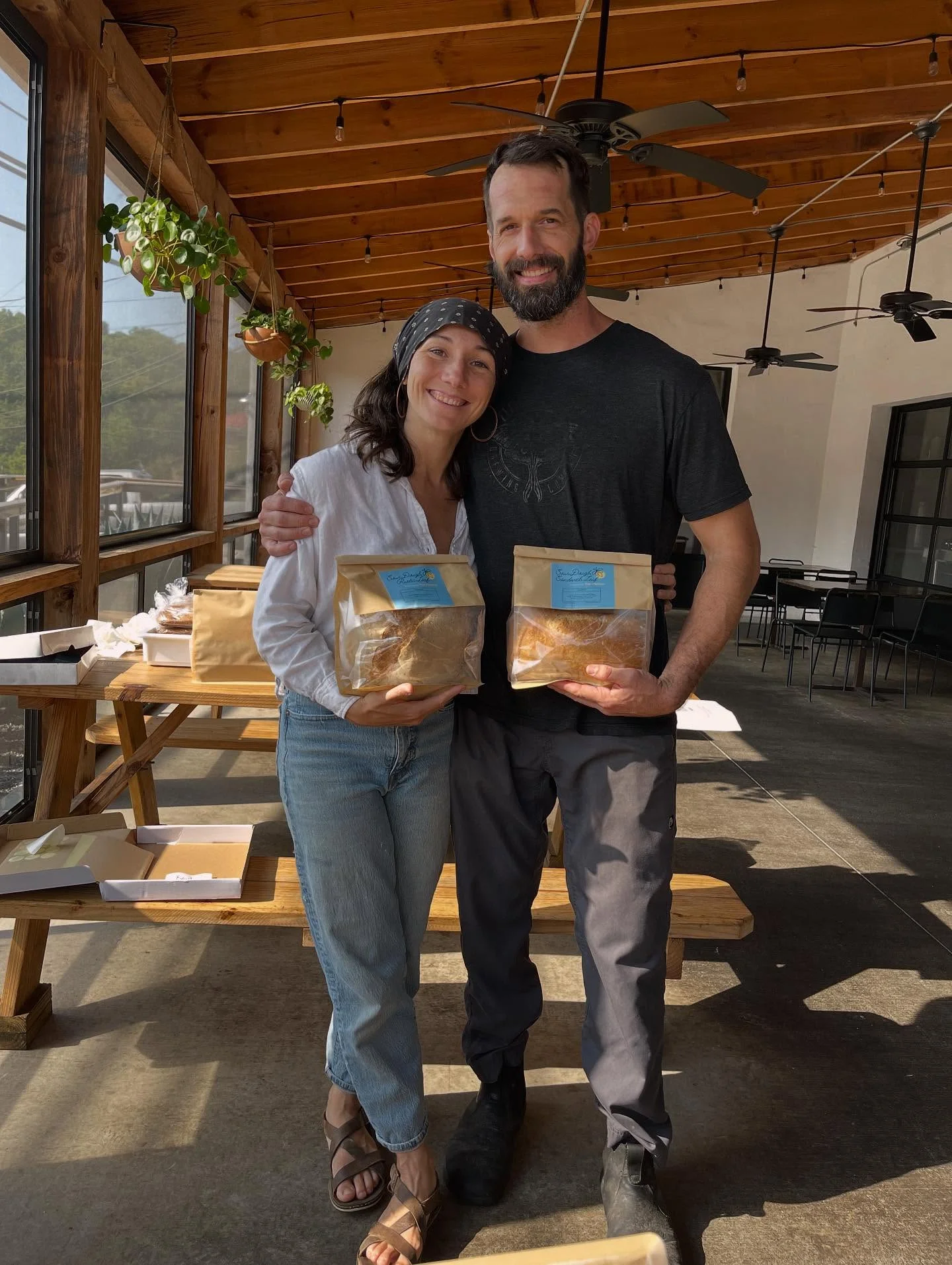 Couple holding bags of artisanal baked goods in a cozy restaurant setting