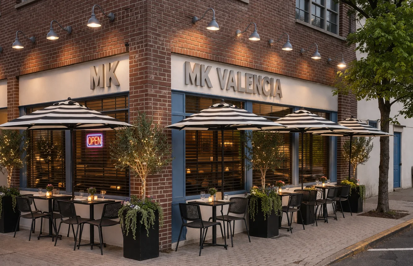 Outdoor dining area of MK Valencia with striped umbrellas and open sign.