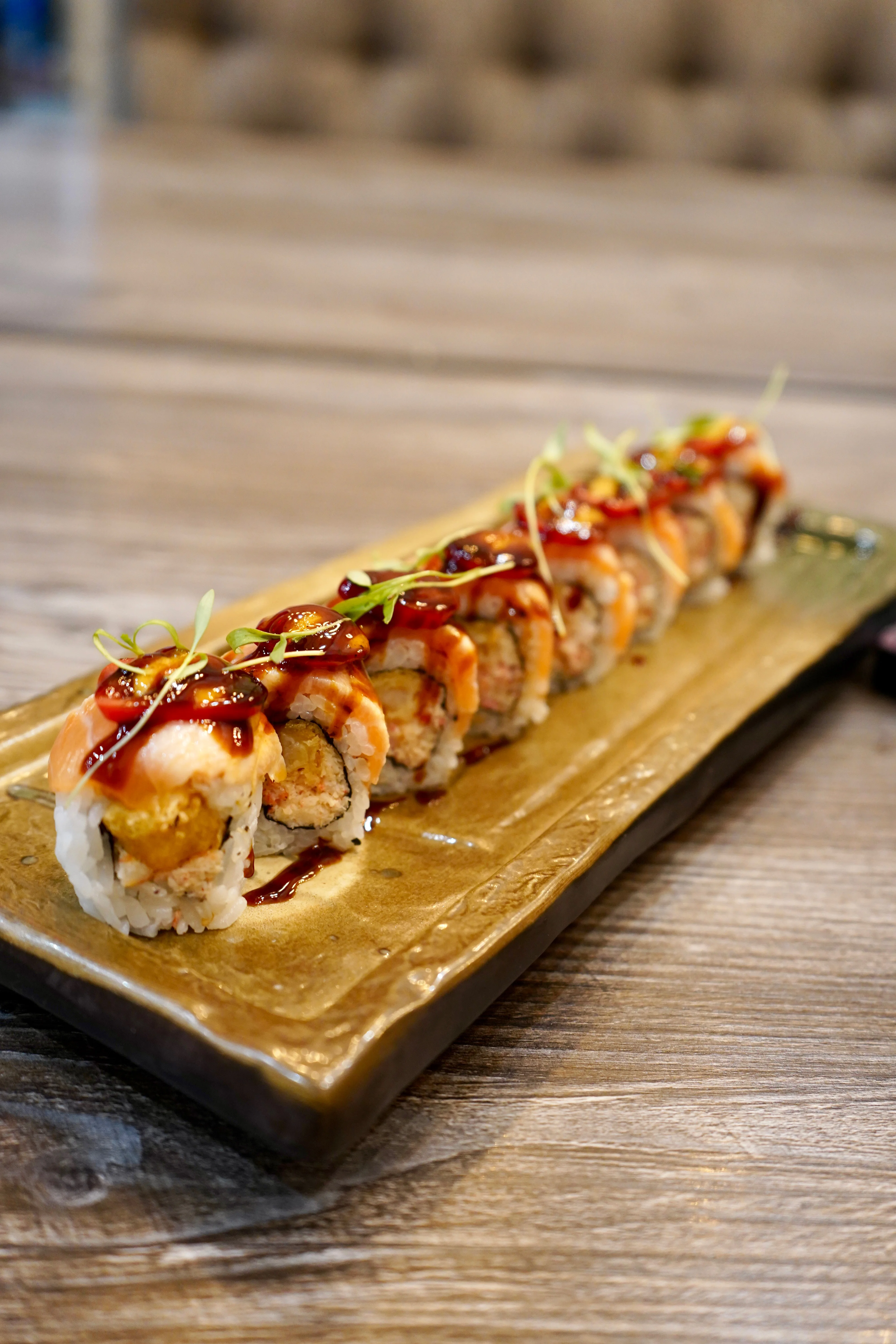 Blurry close-up of assorted sushi rolls on a wooden serving board