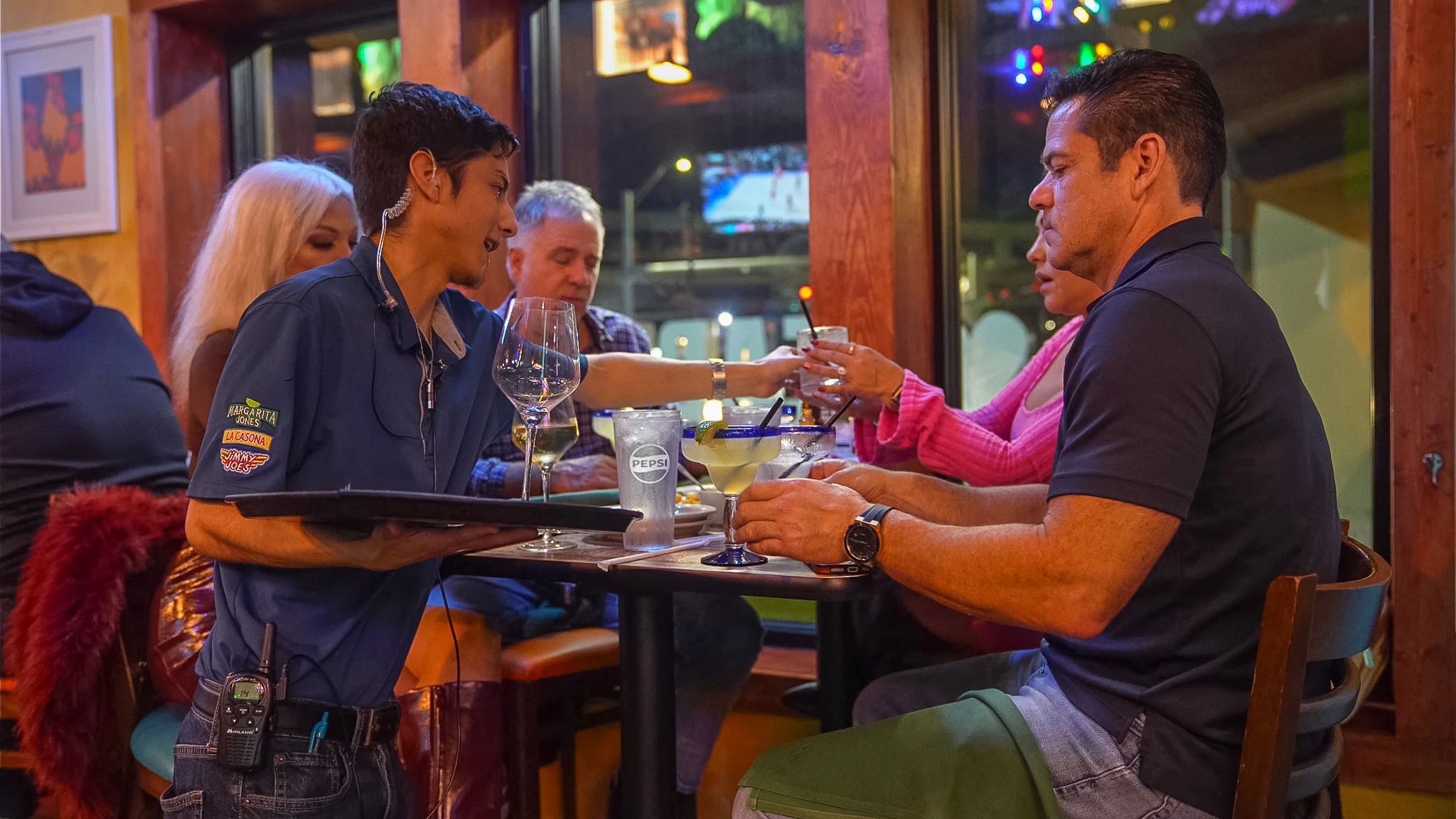 Cozy restaurant scene with attentive server and guests enjoying drinks