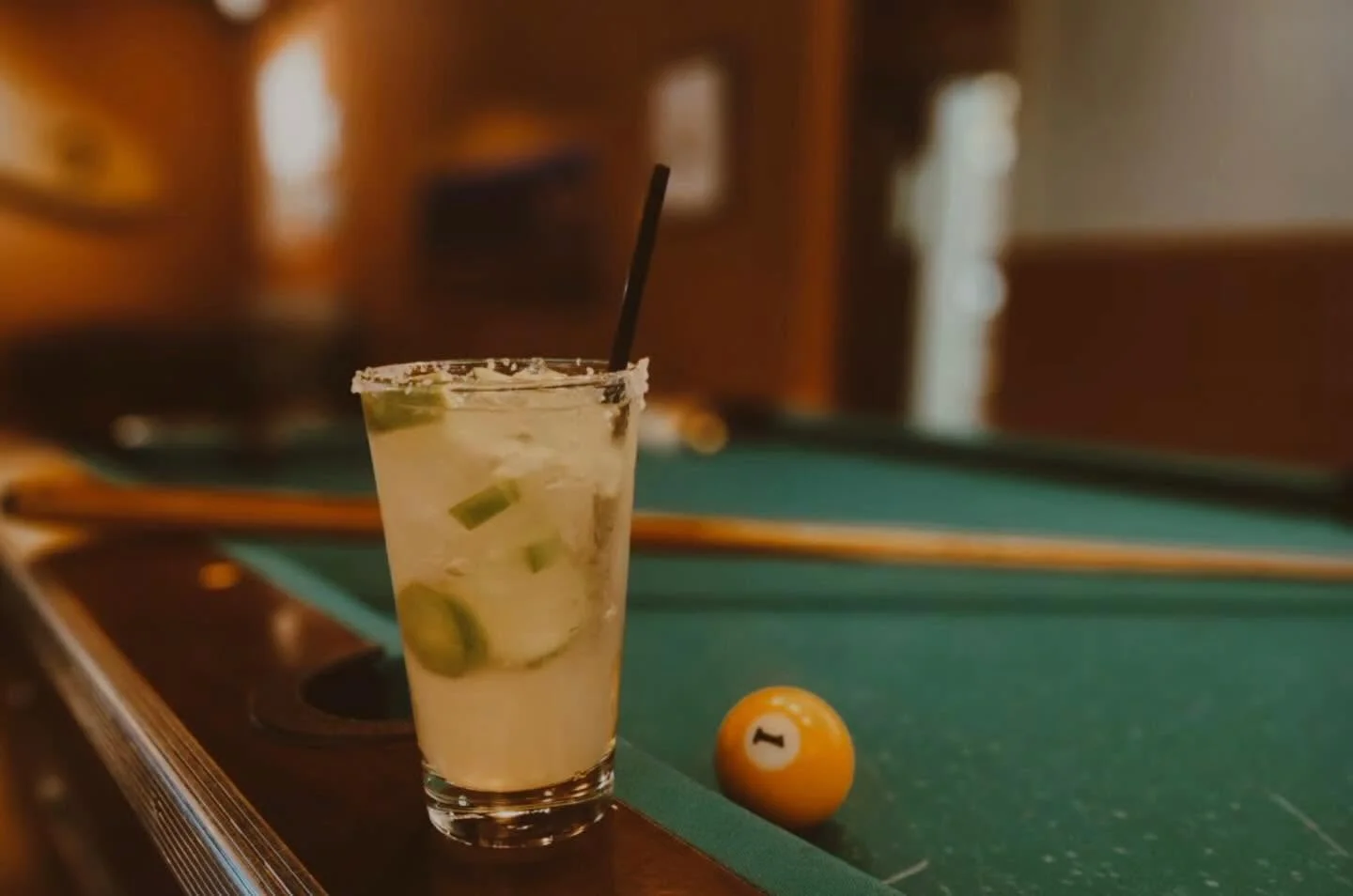 Classic margarita on a pool table in a warmly lit bar