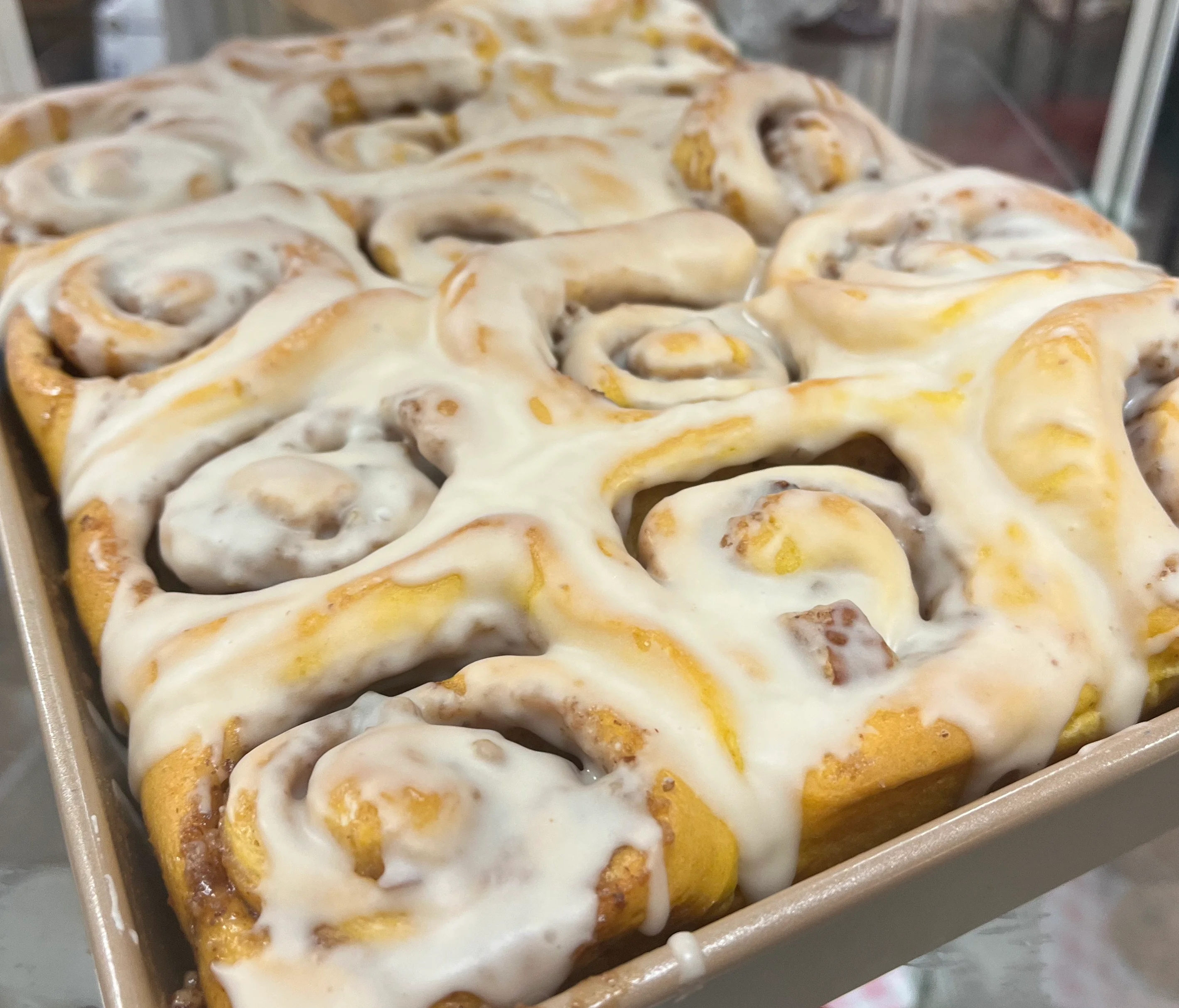 A pan of homemade cinnamon rolls covered in icing.