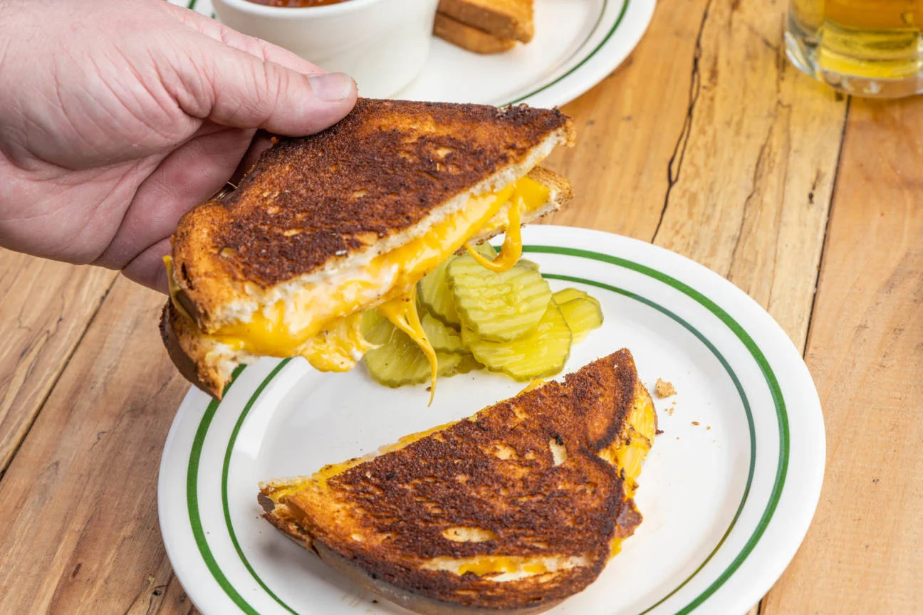Grilled cheese sandwich with pickles on a rustic plate