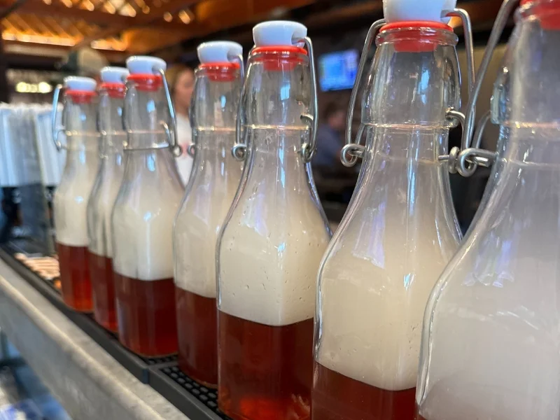 Craft beer bottles with frothy heads on a bar counter