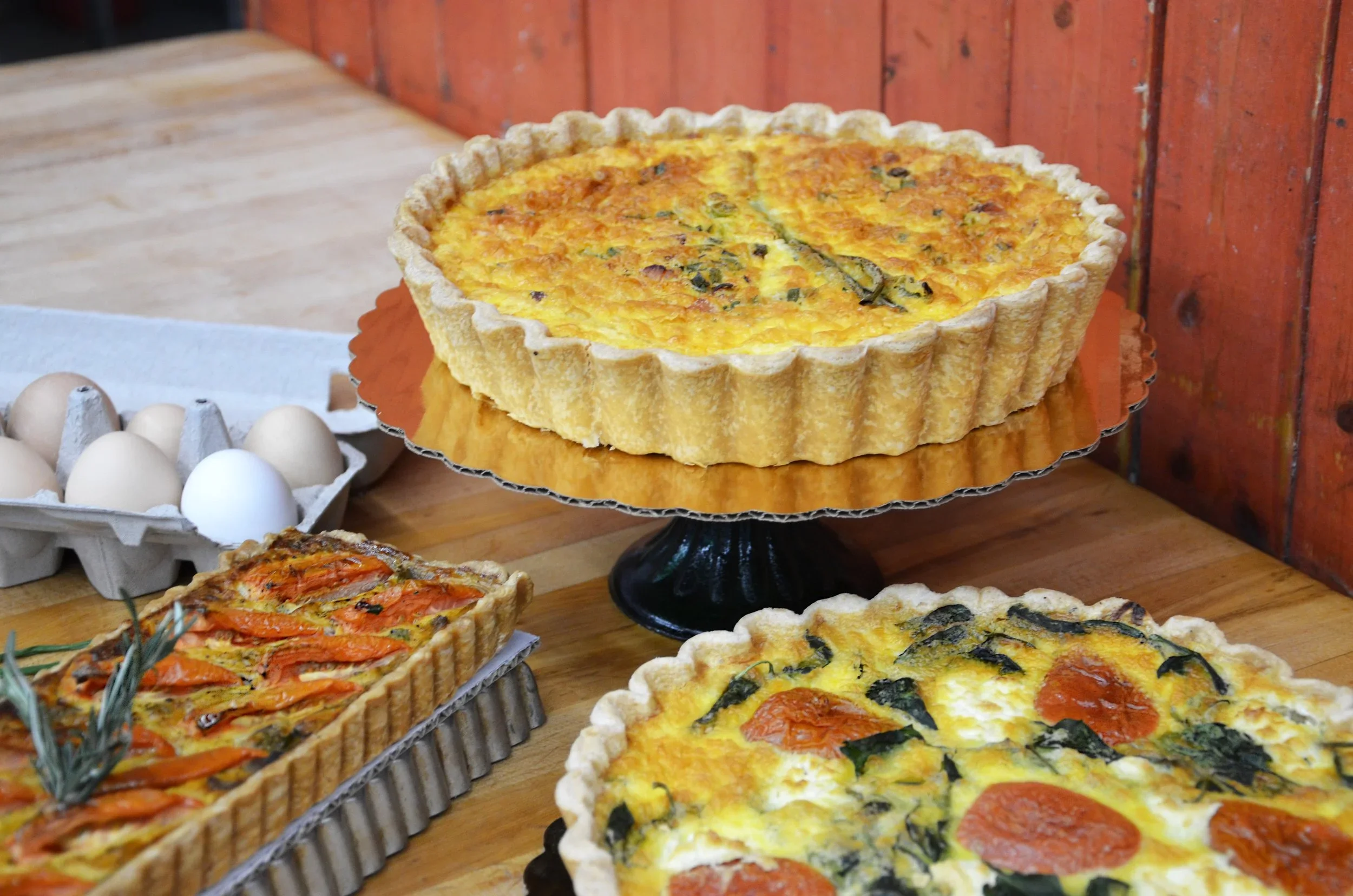 Delicious quiches and tarts displayed on a wooden table.