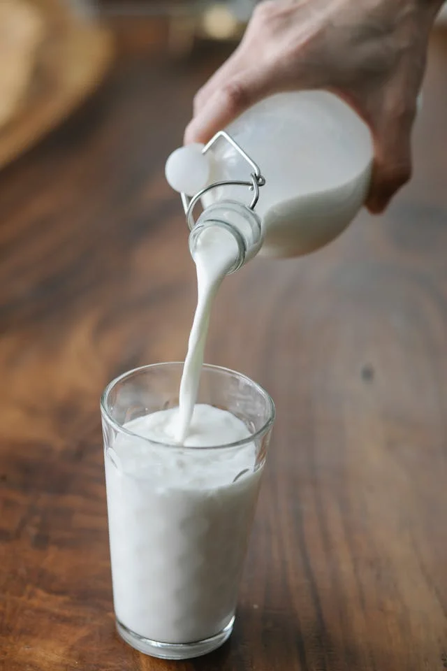 Pouring fresh milk into a glass on a wooden table