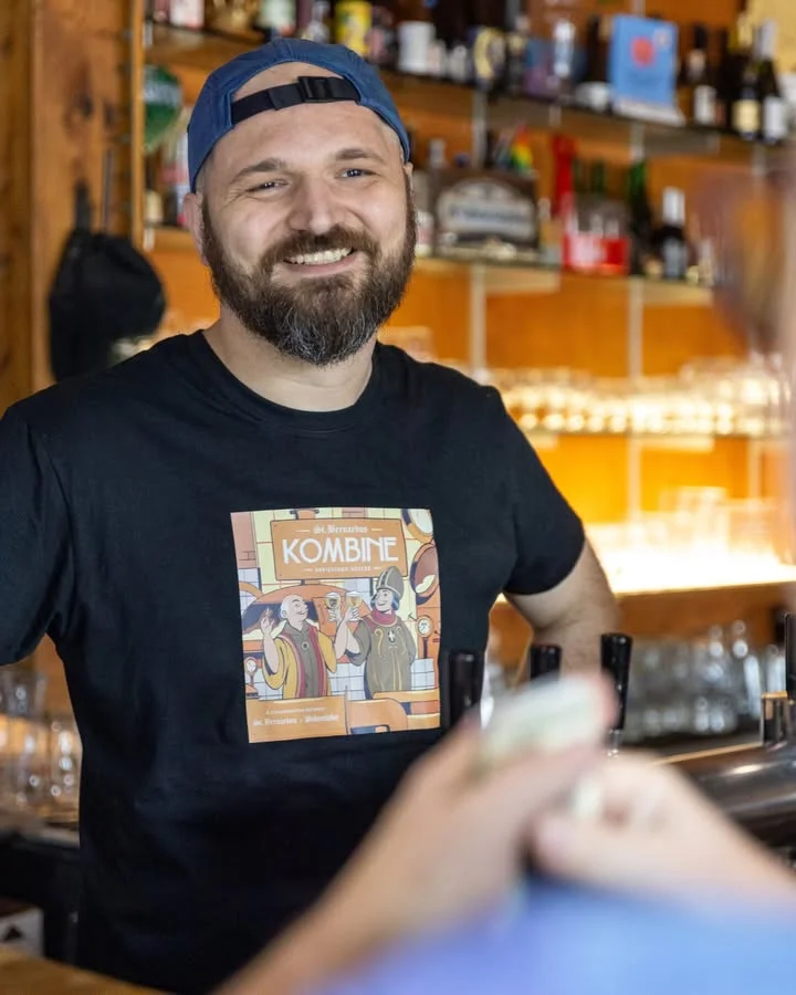Bartender smiling at a bar with a Kombine-themed shirt
