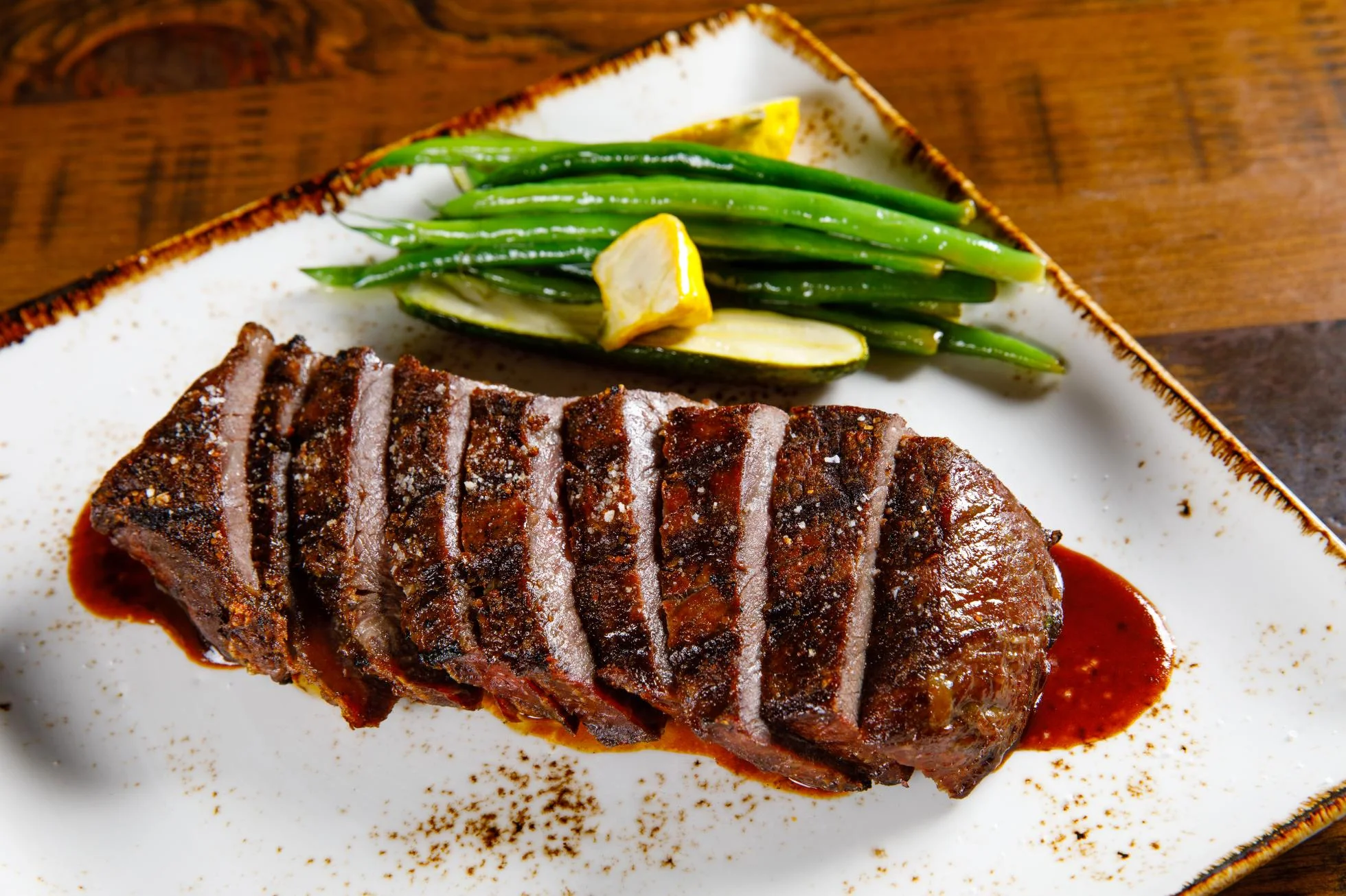 Grilled steak with green beans and lemon garnish