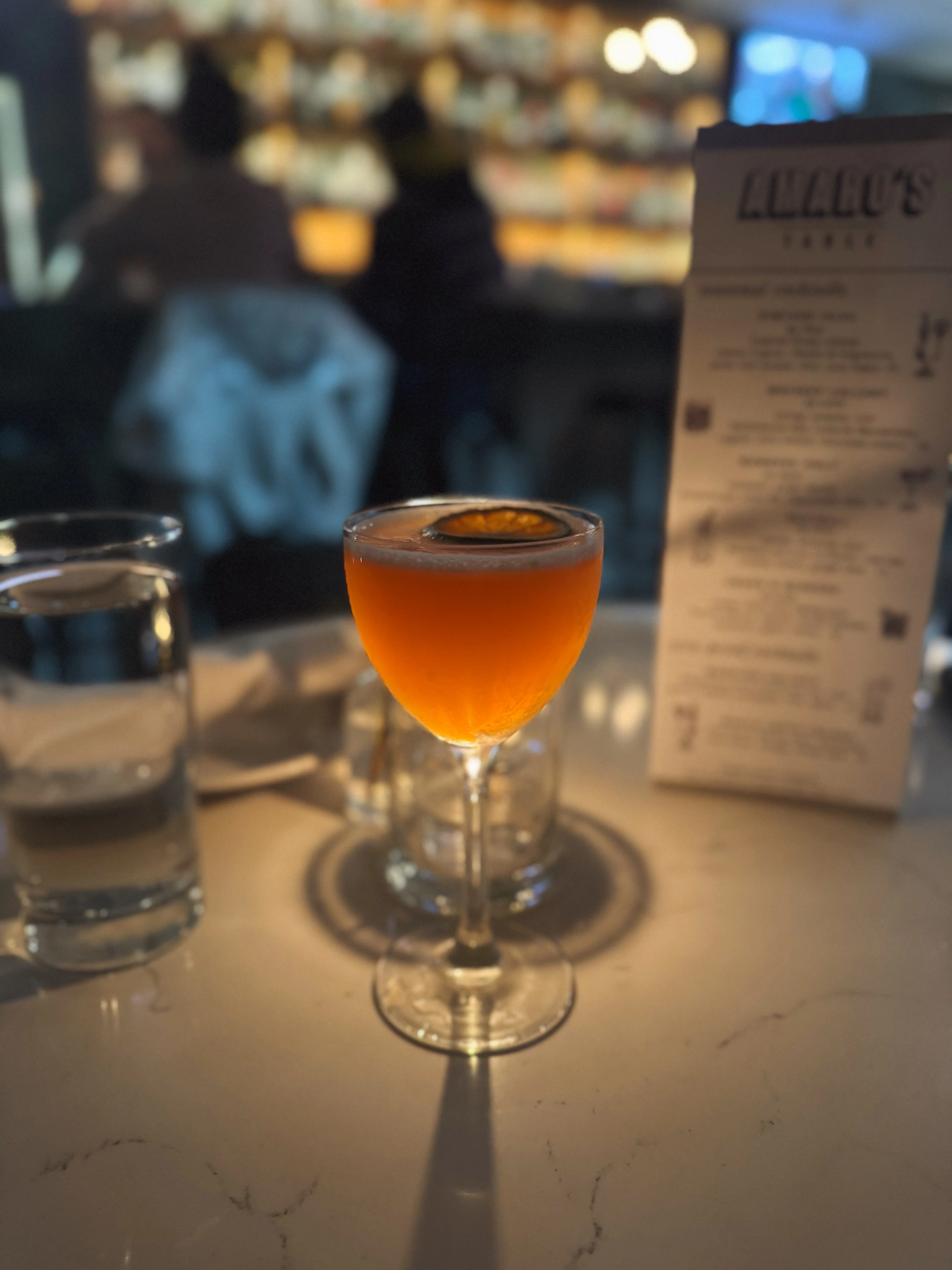Craft cocktail with orange garnish in a stylish bar setting