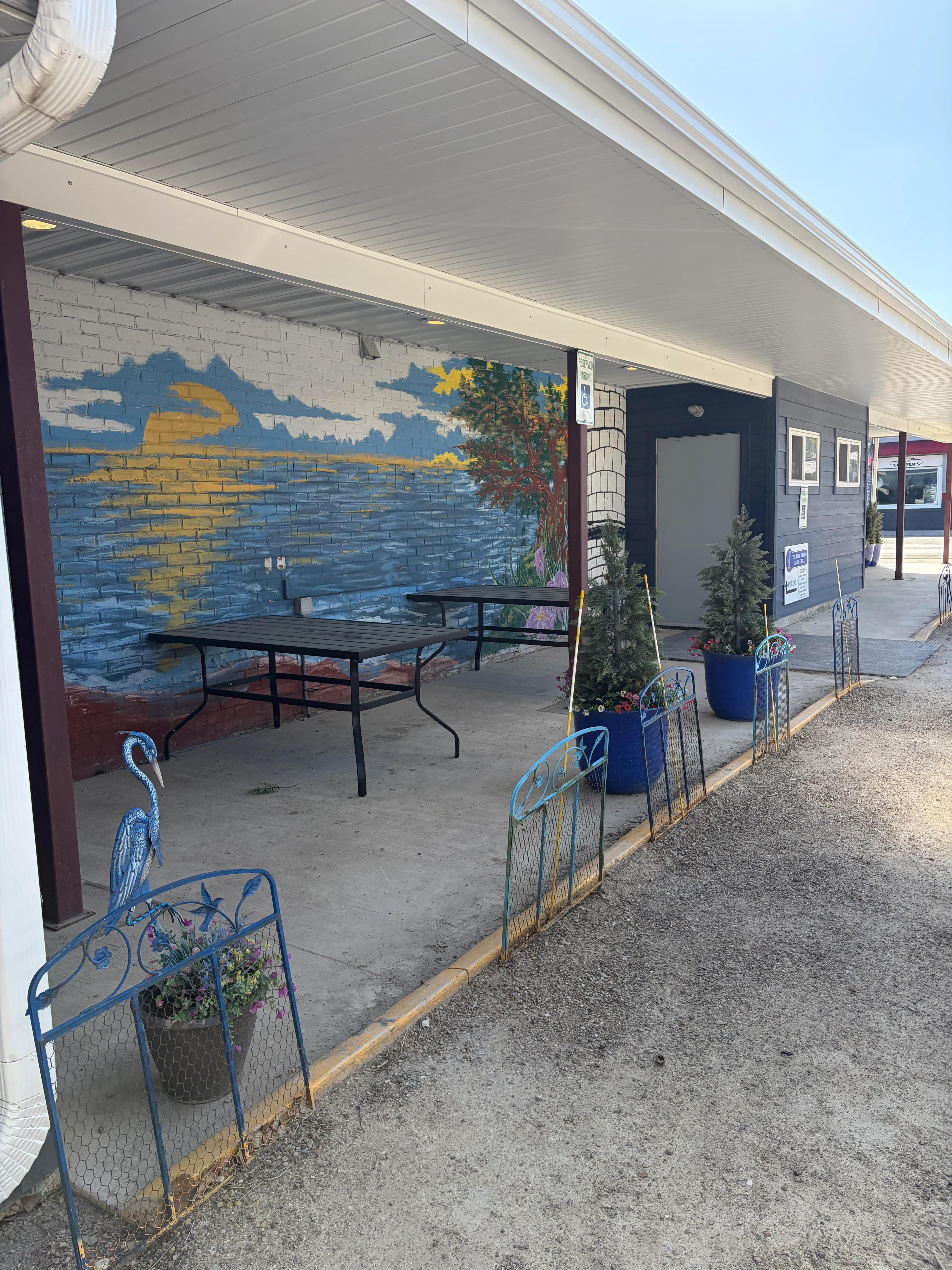 Outdoor seating area with mural and decorative planters at a restaurant.
