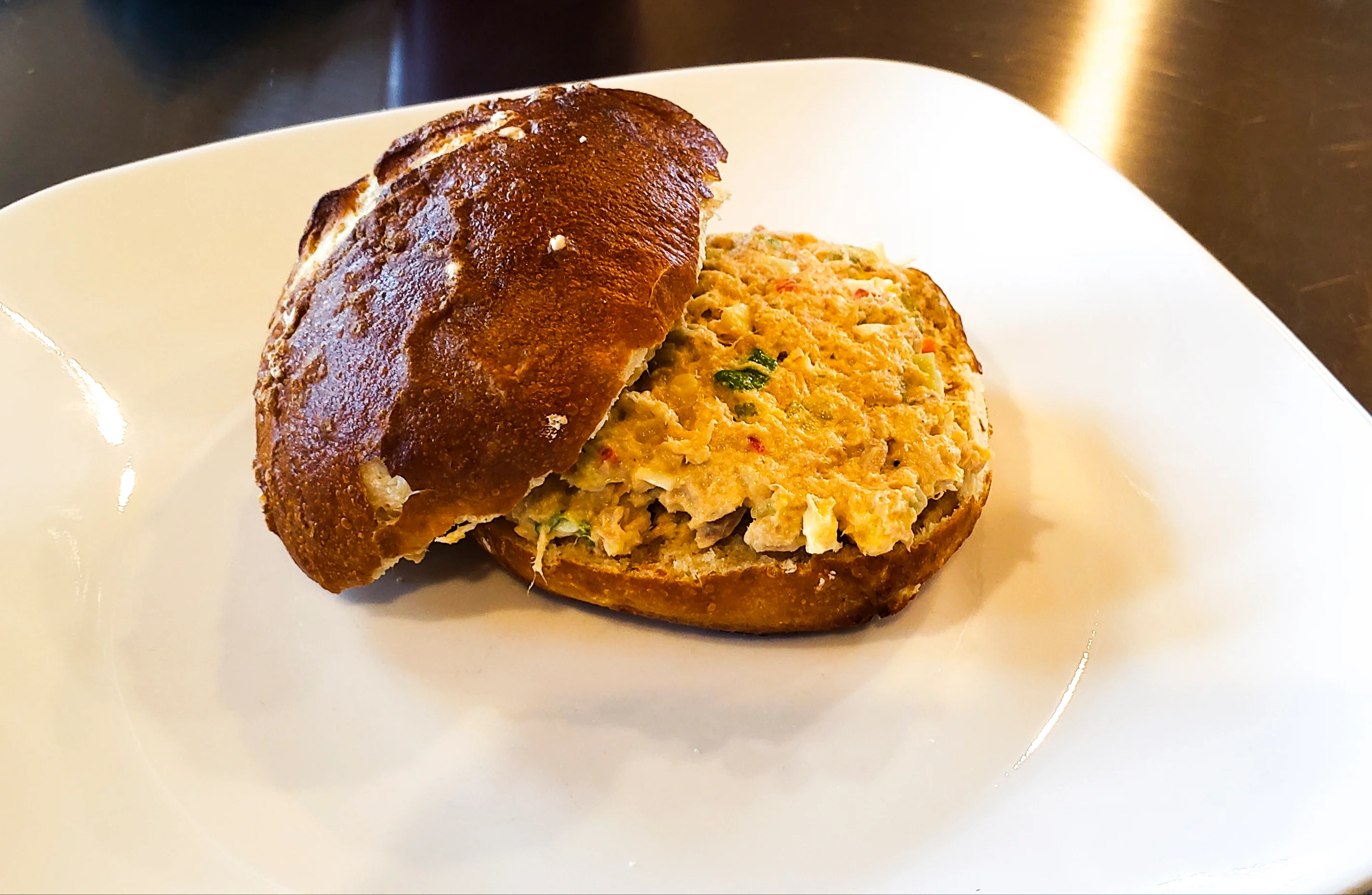 Pretzel bun sandwich filled with a creamy, chunky filling.