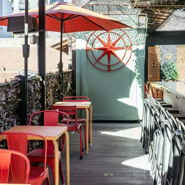 Stylish outdoor dining area with red chairs and umbrellas