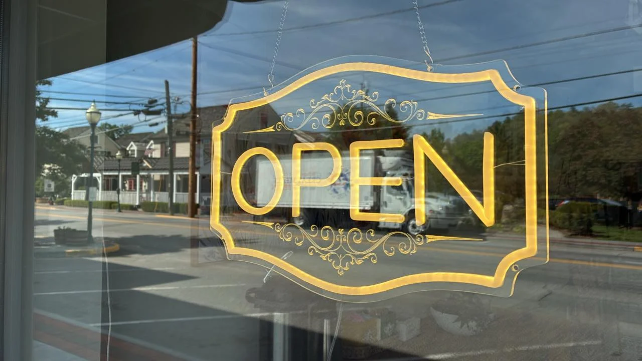 Open sign displayed in a restaurant window with a street view.