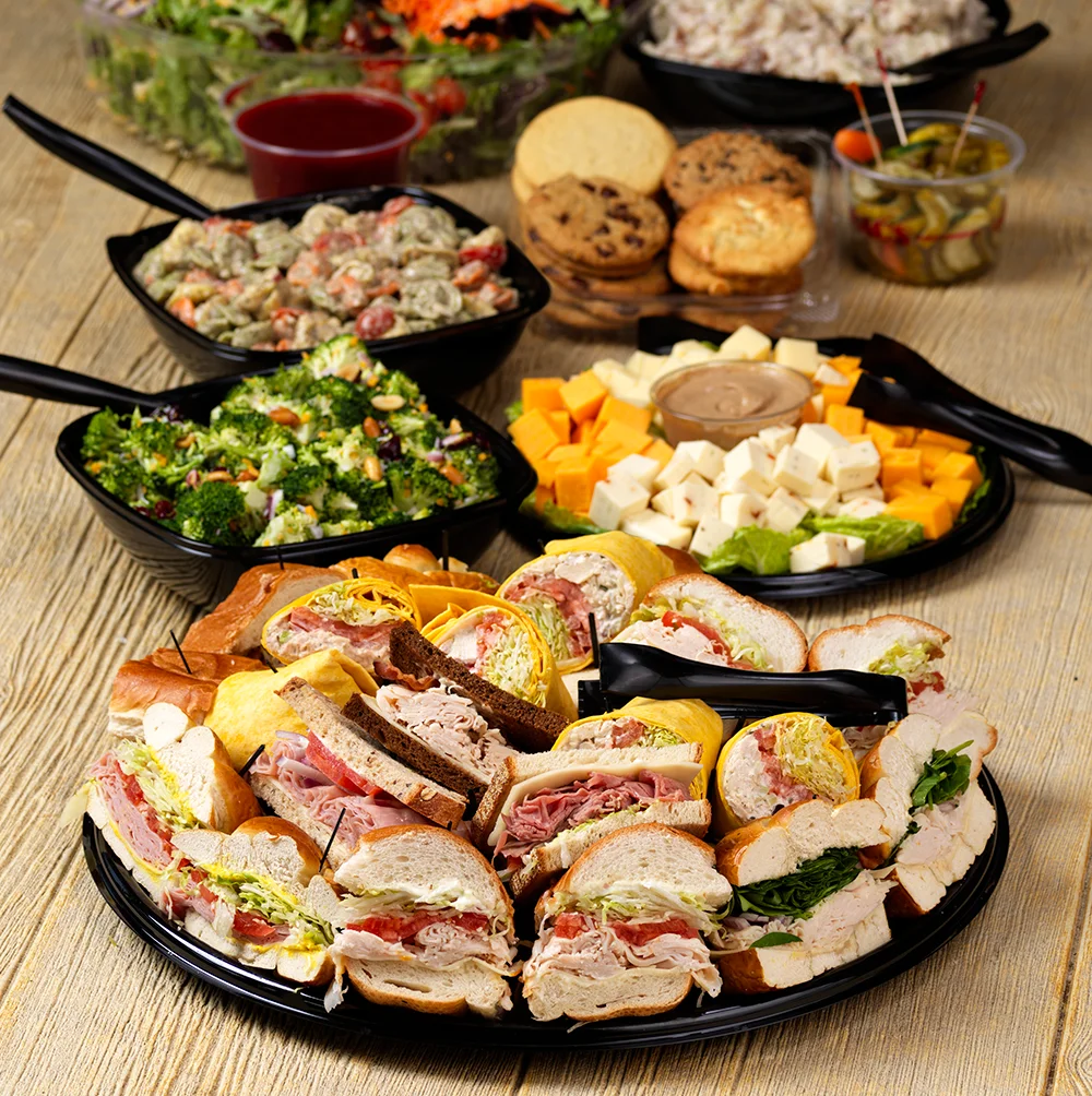 Gourmet sandwich platter from Isaac's Craft Kitchen & Brewery, featuring assorted deli sandwiches, wraps, fresh veggies, and artisan bread, served with broccoli salad and a cheese tray. Perfect for catering and events.