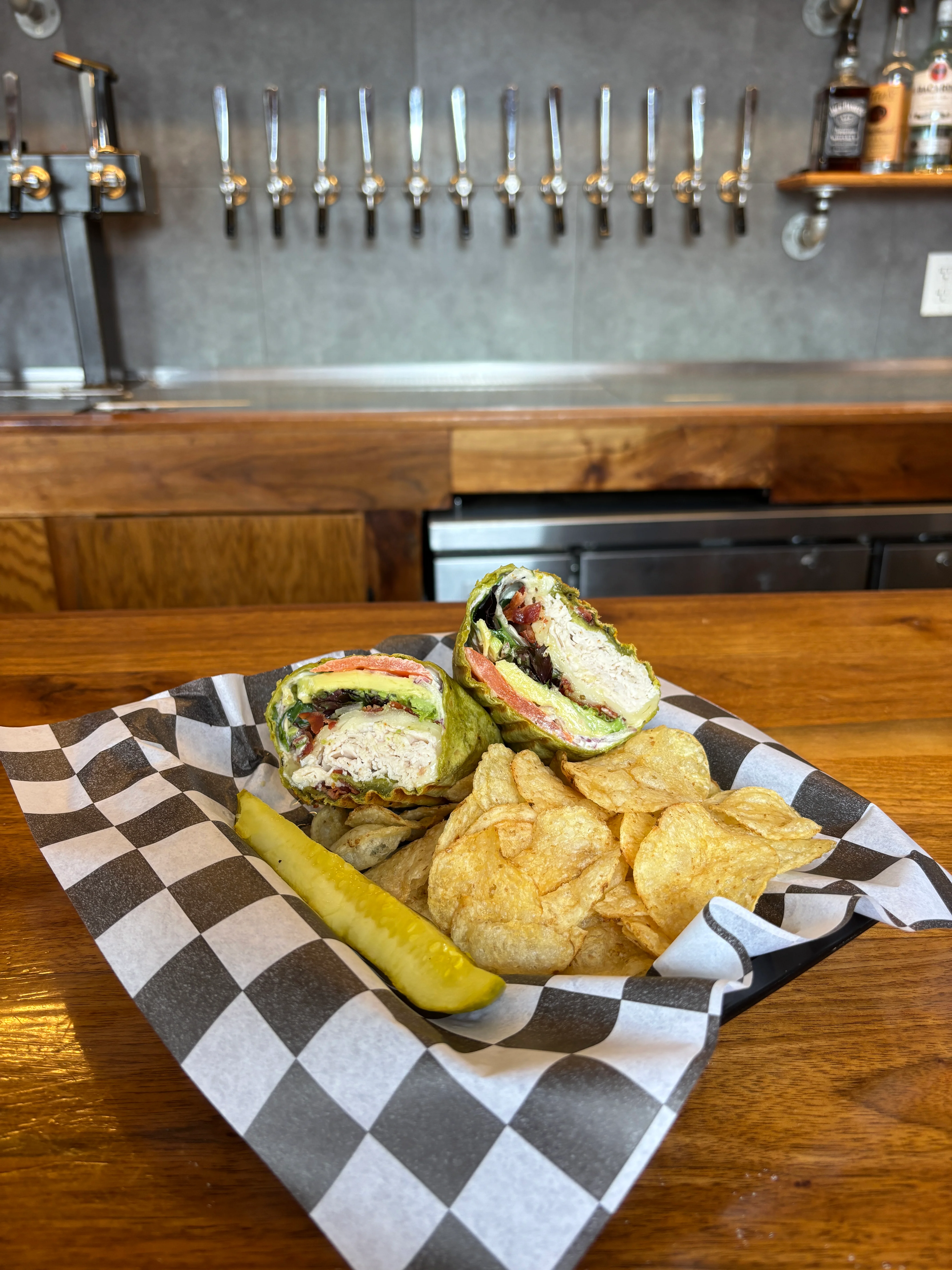Fresh chicken wrap with lettuce and tomato served with chips and pickle