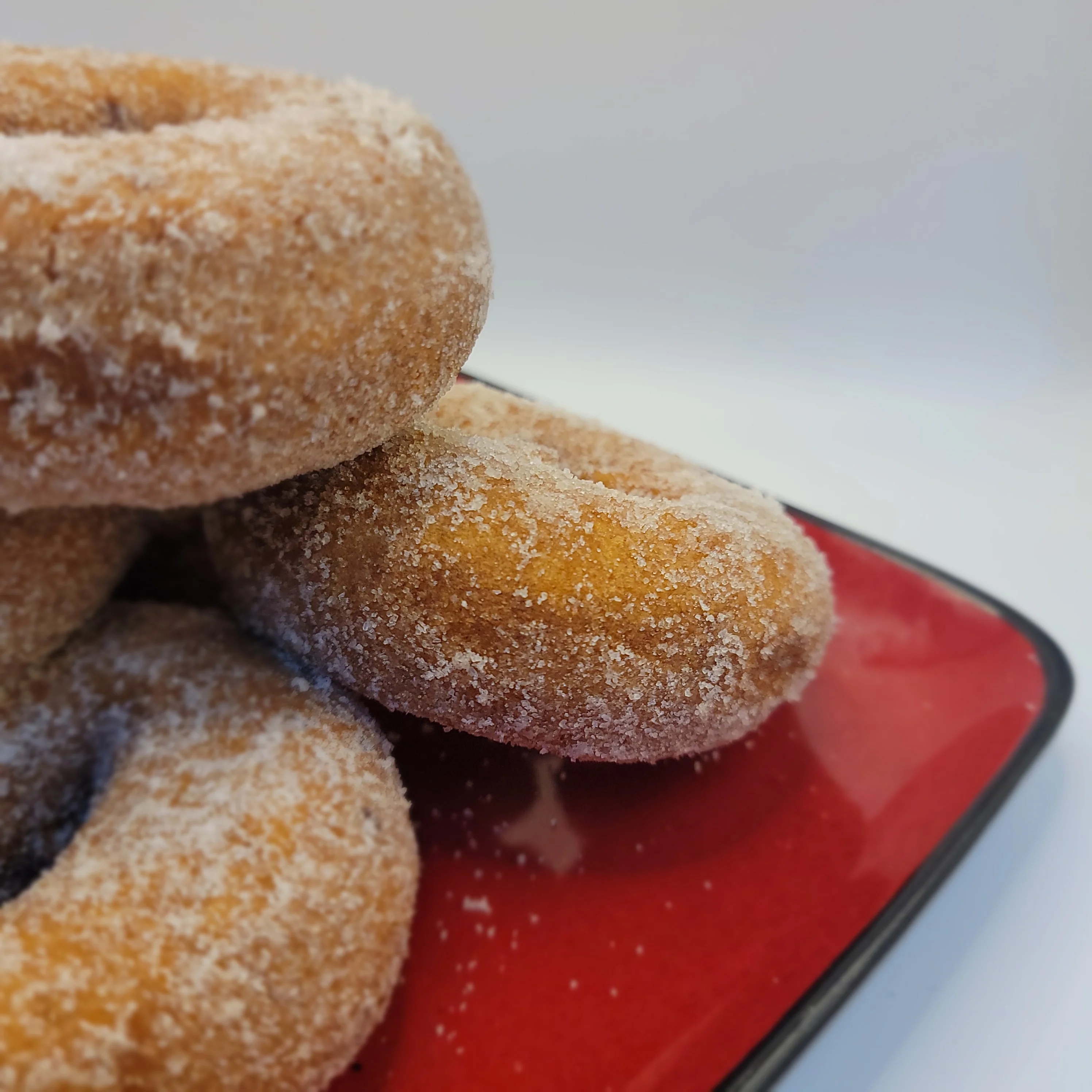 Freshly made sugar-coated donuts on a red plate