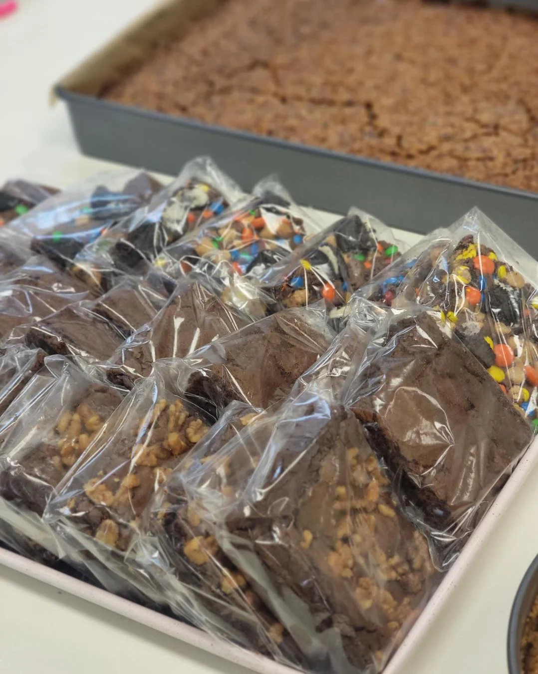 Trays of brownies, some topped with nuts, others with colorful candies and Oreo pieces.