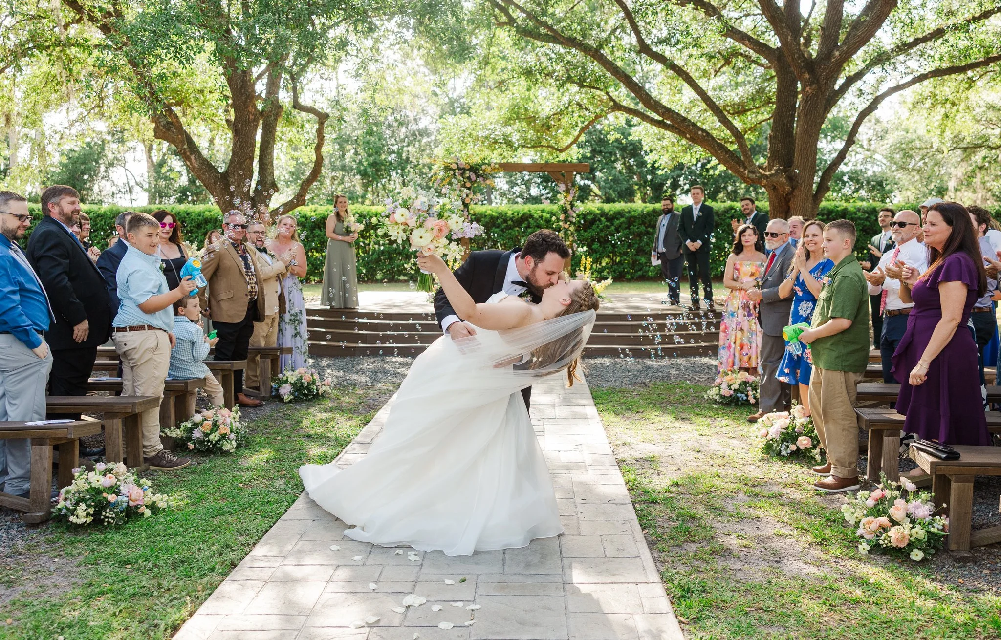 Couple sharing a romantic kiss at their outdoor wedding ceremony
