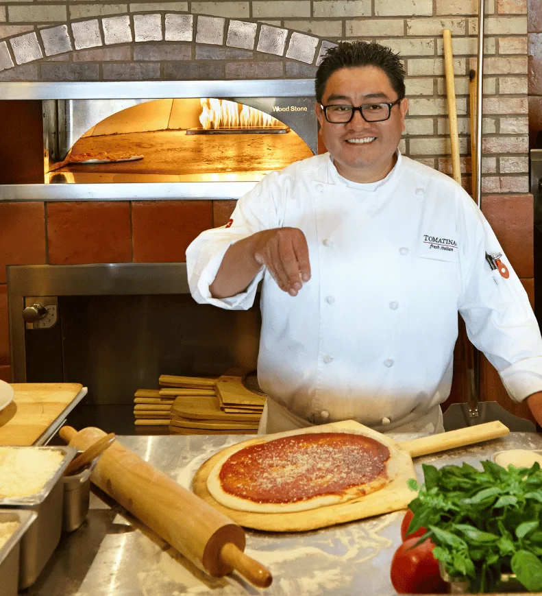 Chef sprinkling cheese on pizza