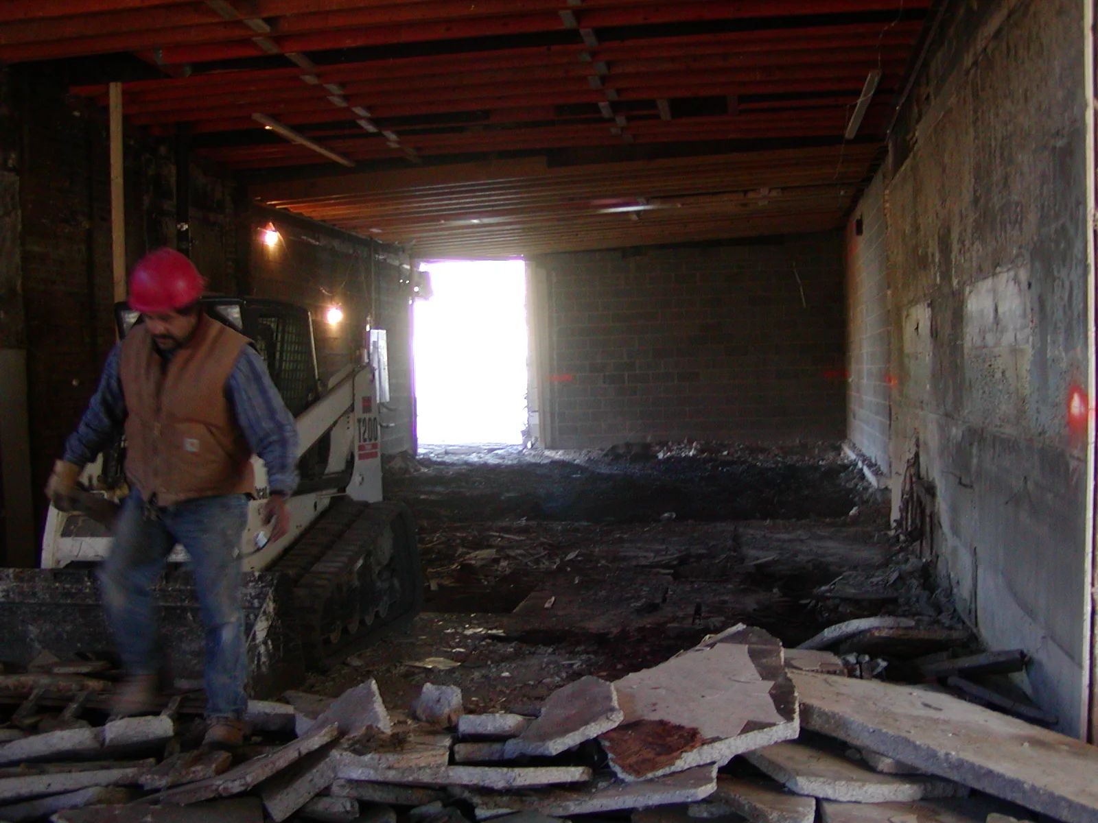 Construction site with worker and machinery in a partially demolished interior space