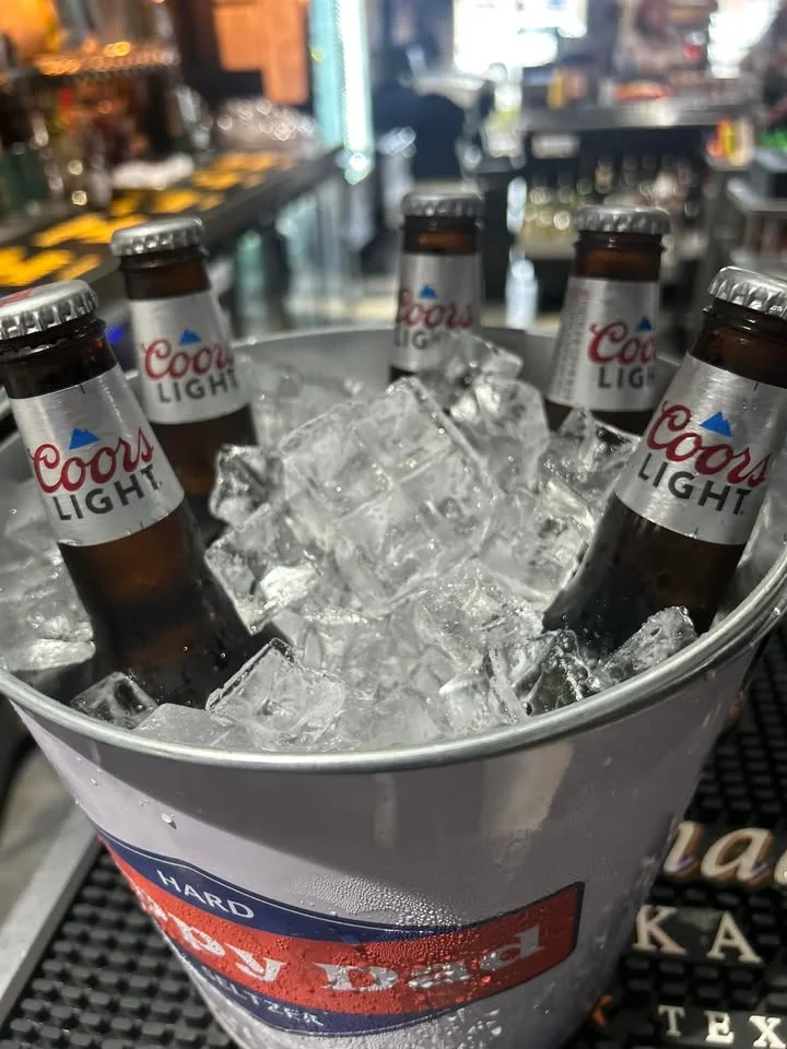Chilled Coors Light beers in an ice bucket at a bar
