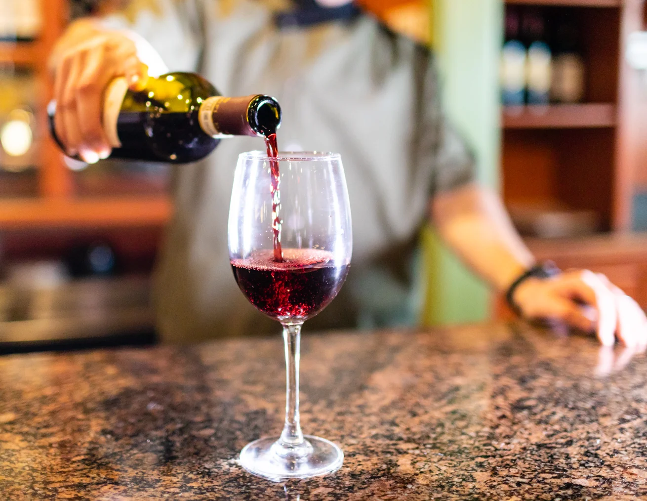 Bartender pouring red wine into a glass at a stylish bar