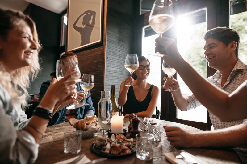 Group of friends toasting with wine glasses in a cozy restaurant