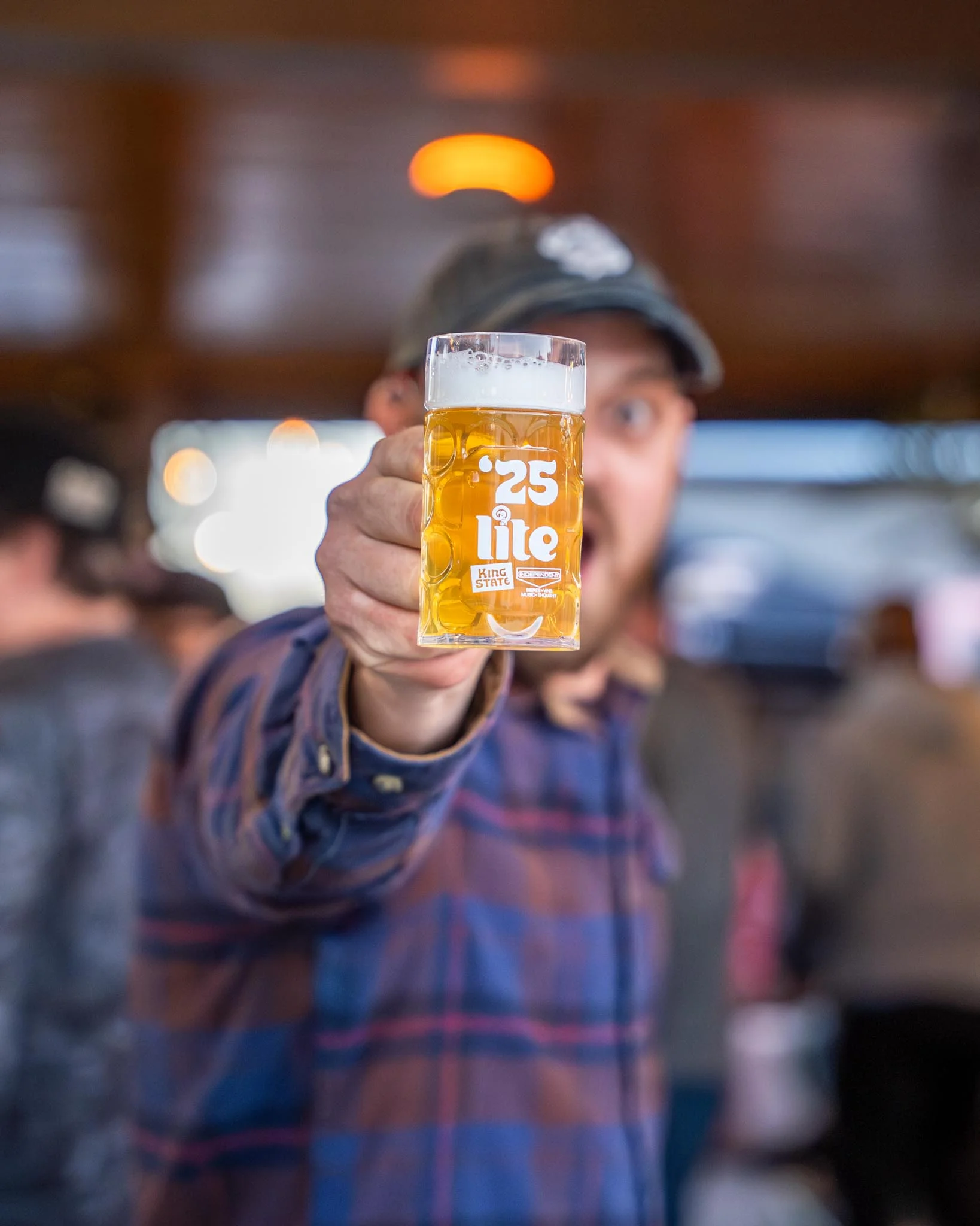 Person holding a glass of beer at a lively bar atmosphere
