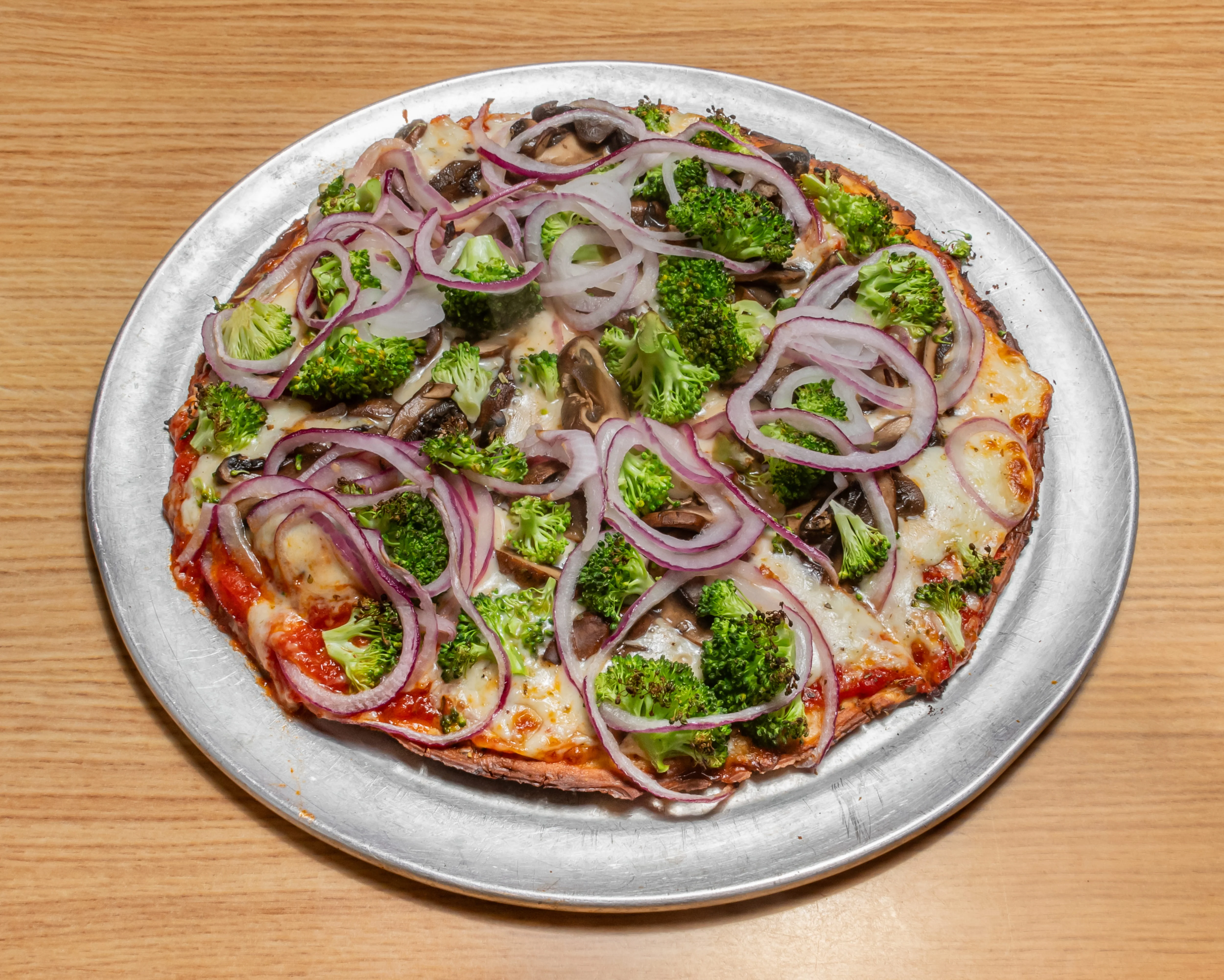 Cauliflower crust veggie pizza topped with colorful vegetables.