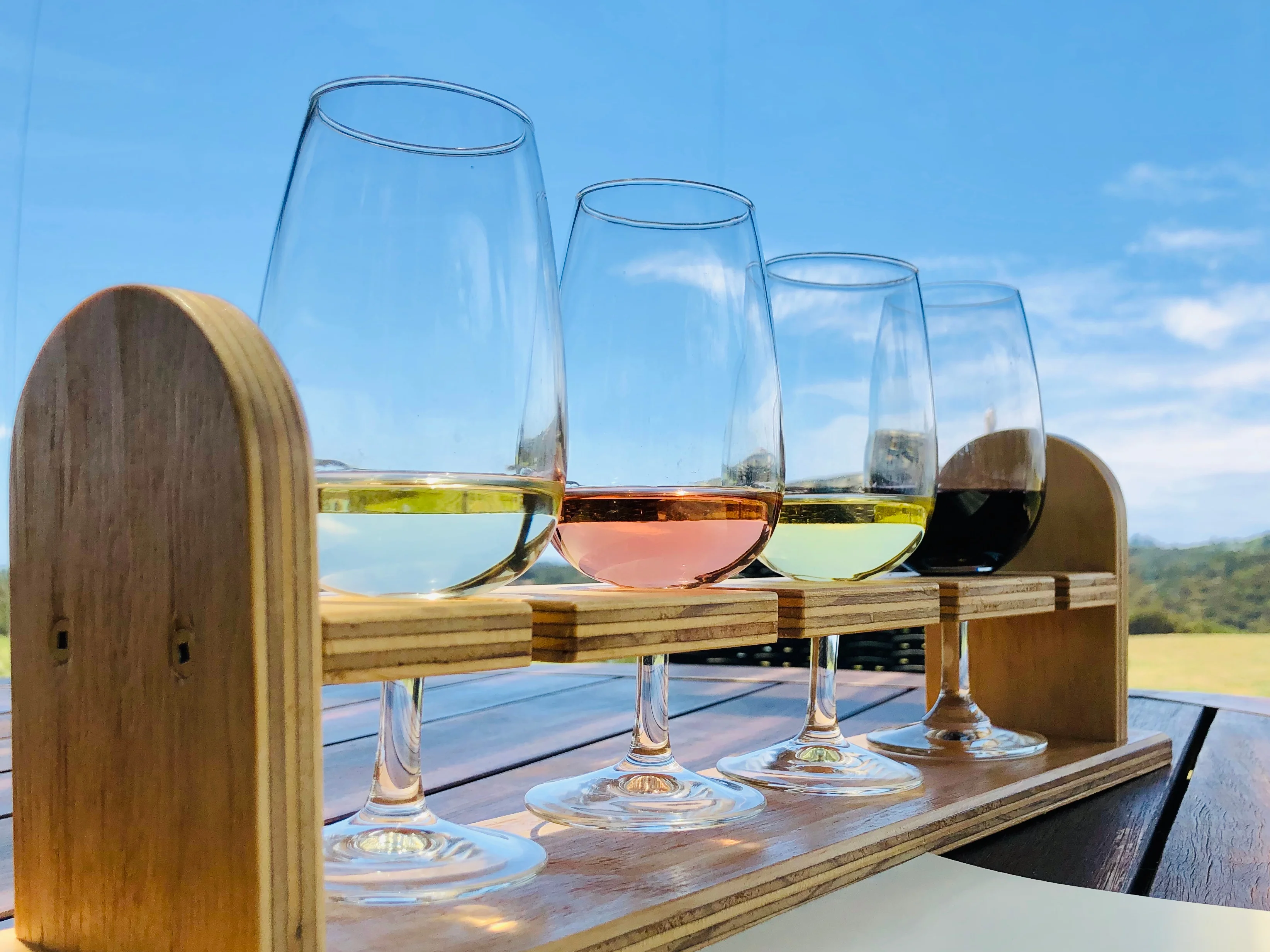A selection of wine glasses being filled with various types of wine from an open bottle.