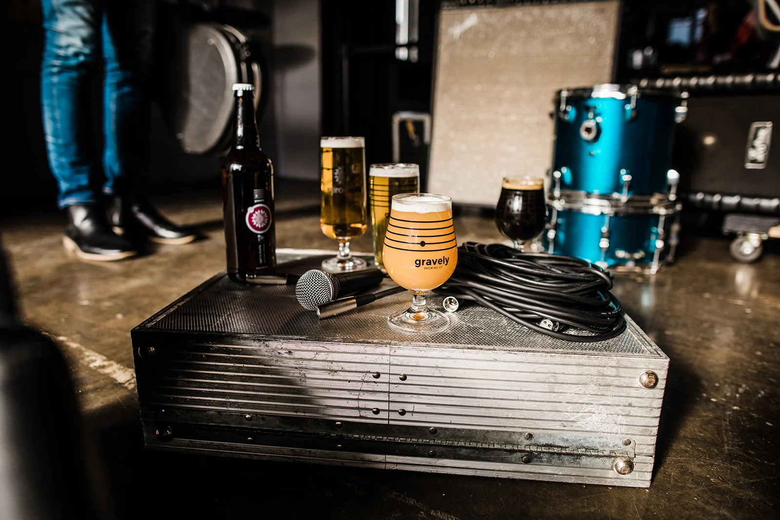 Assorted craft beers on a music equipment case with a microphone.